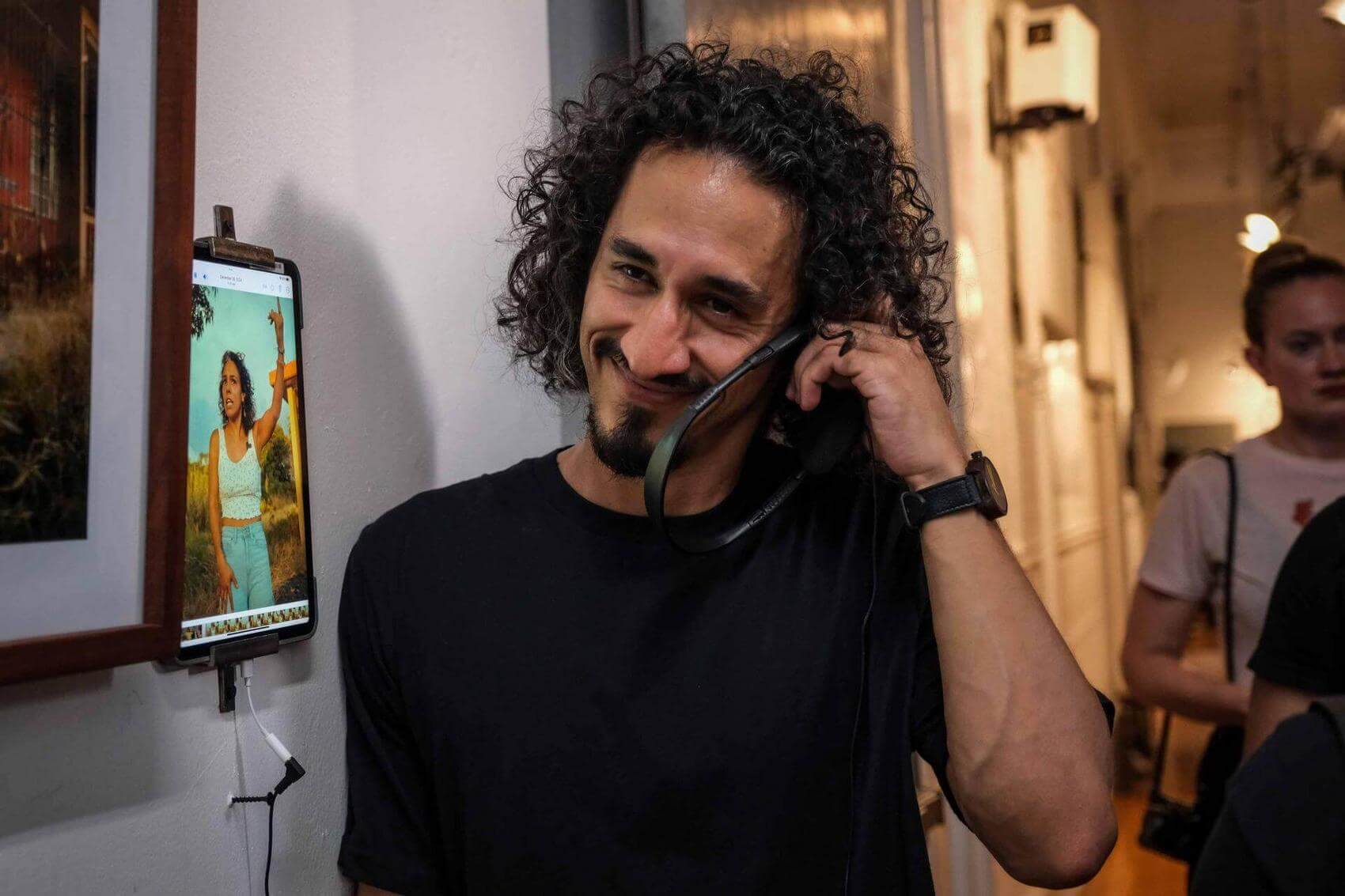 Two women, one young and one older, laughing and holding hands while enjoying music in a lively street setting with musicians in the background.