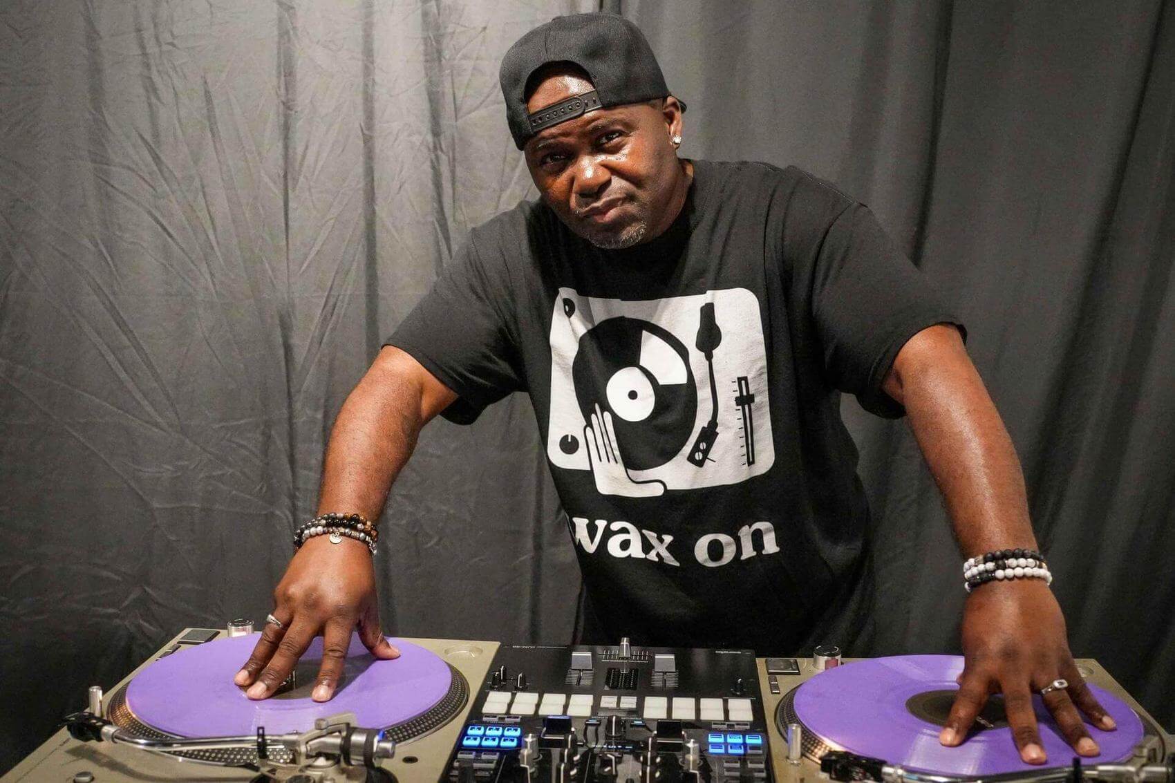 A teenager and a young child sit on the floor in a dance studio, engaging in conversation.