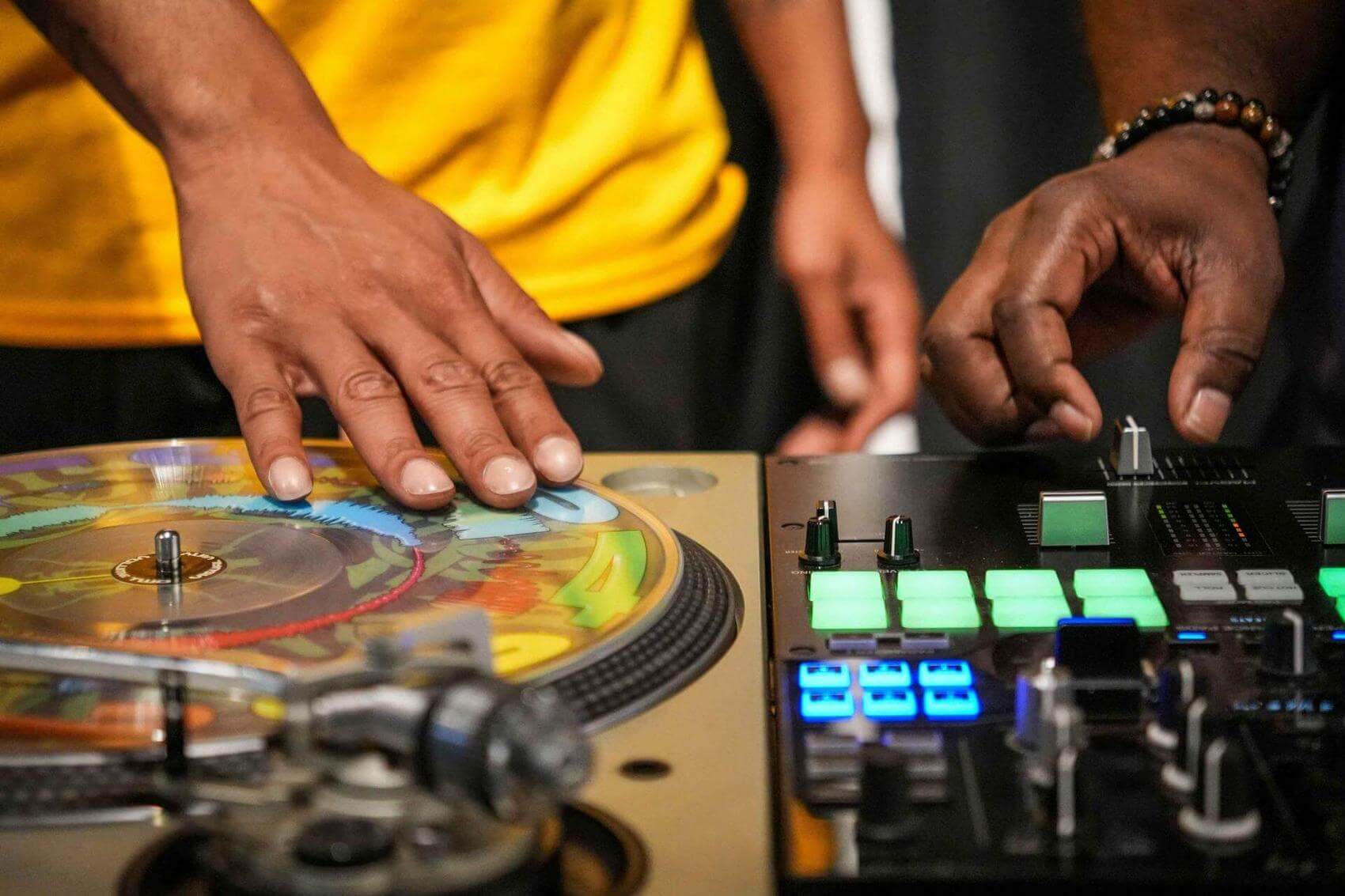 Two dancers practicing together indoors, with one man in a yellow shirt and one girl in a black shirt.