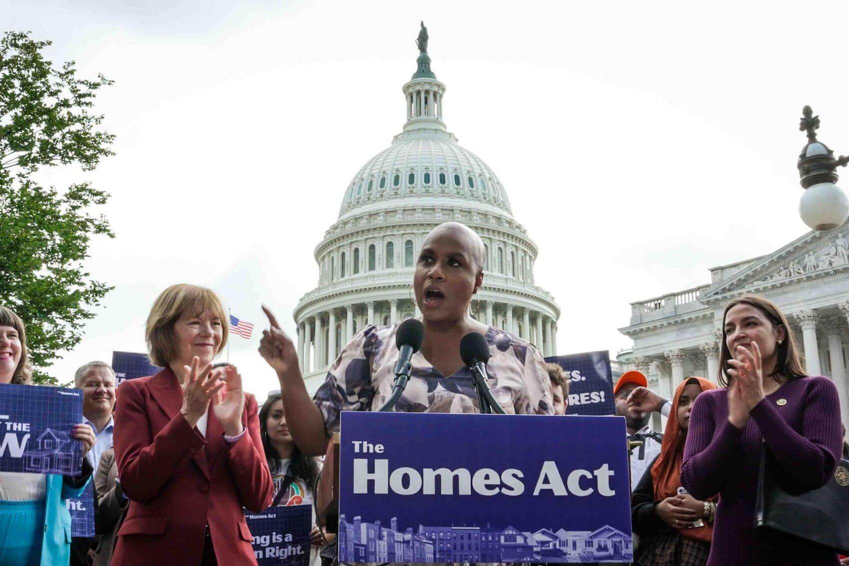 Group of people holding signs advocating for housing rights at a rally.