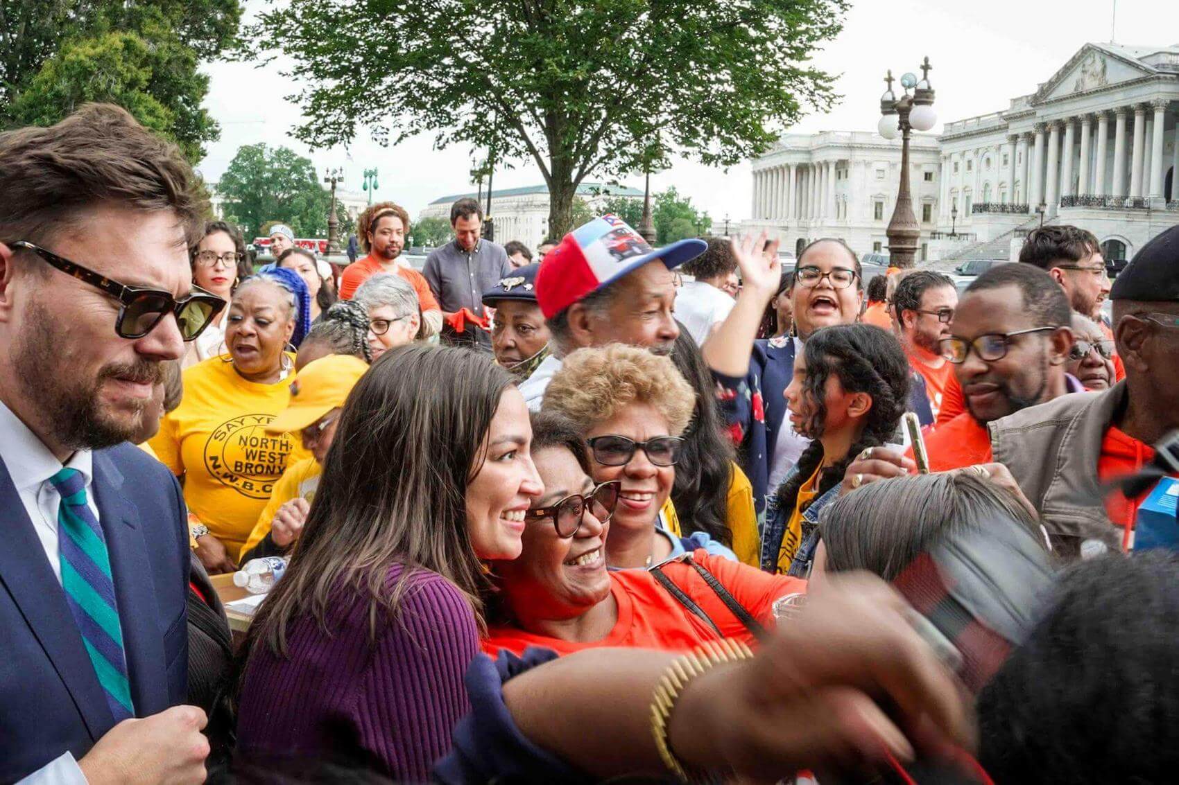 Person waving in a room with ornate decor; screen displays "Housing is a Human Right."