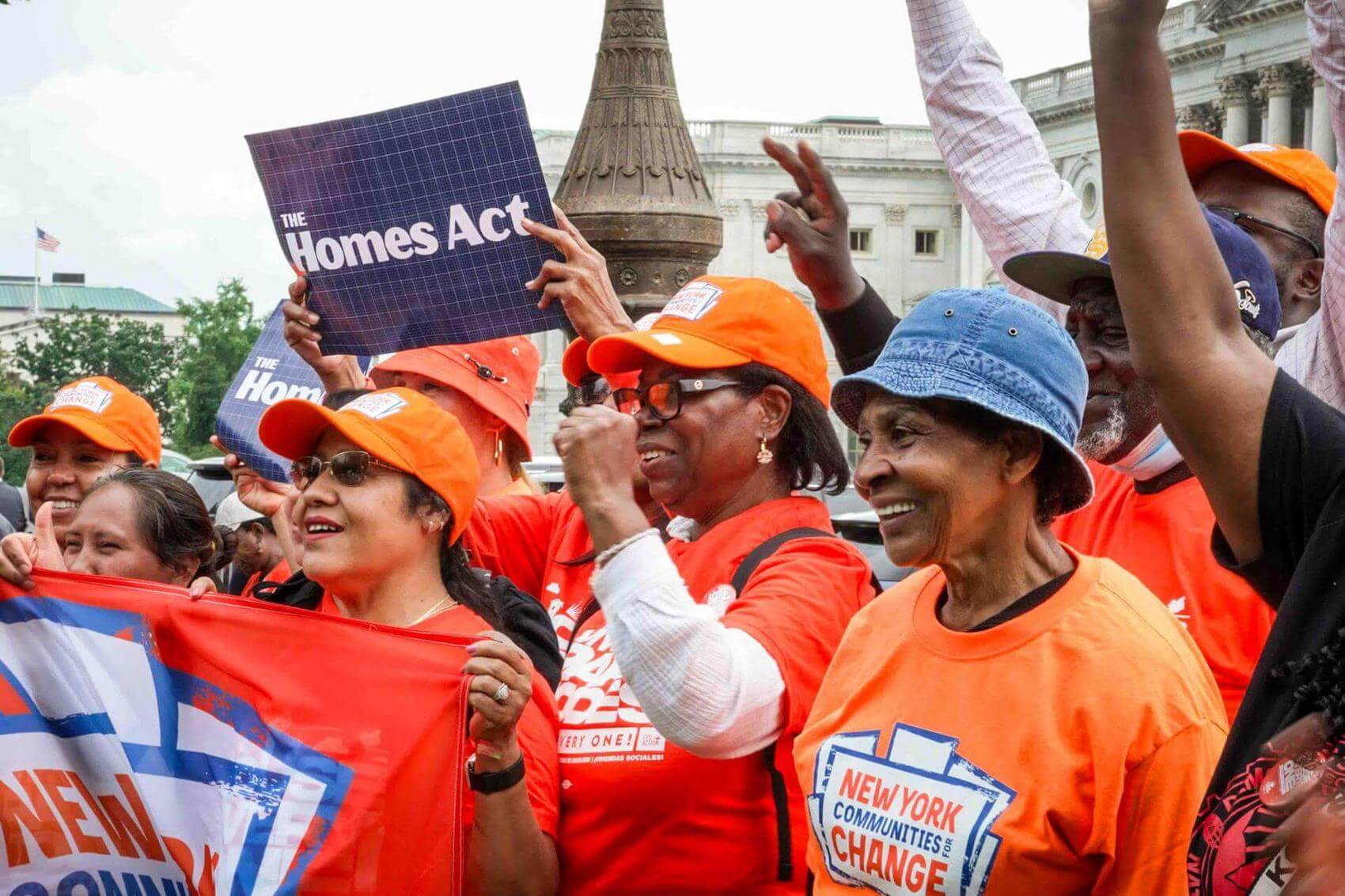 Group of protesters holding signs and a banner advocating for affordable housing.