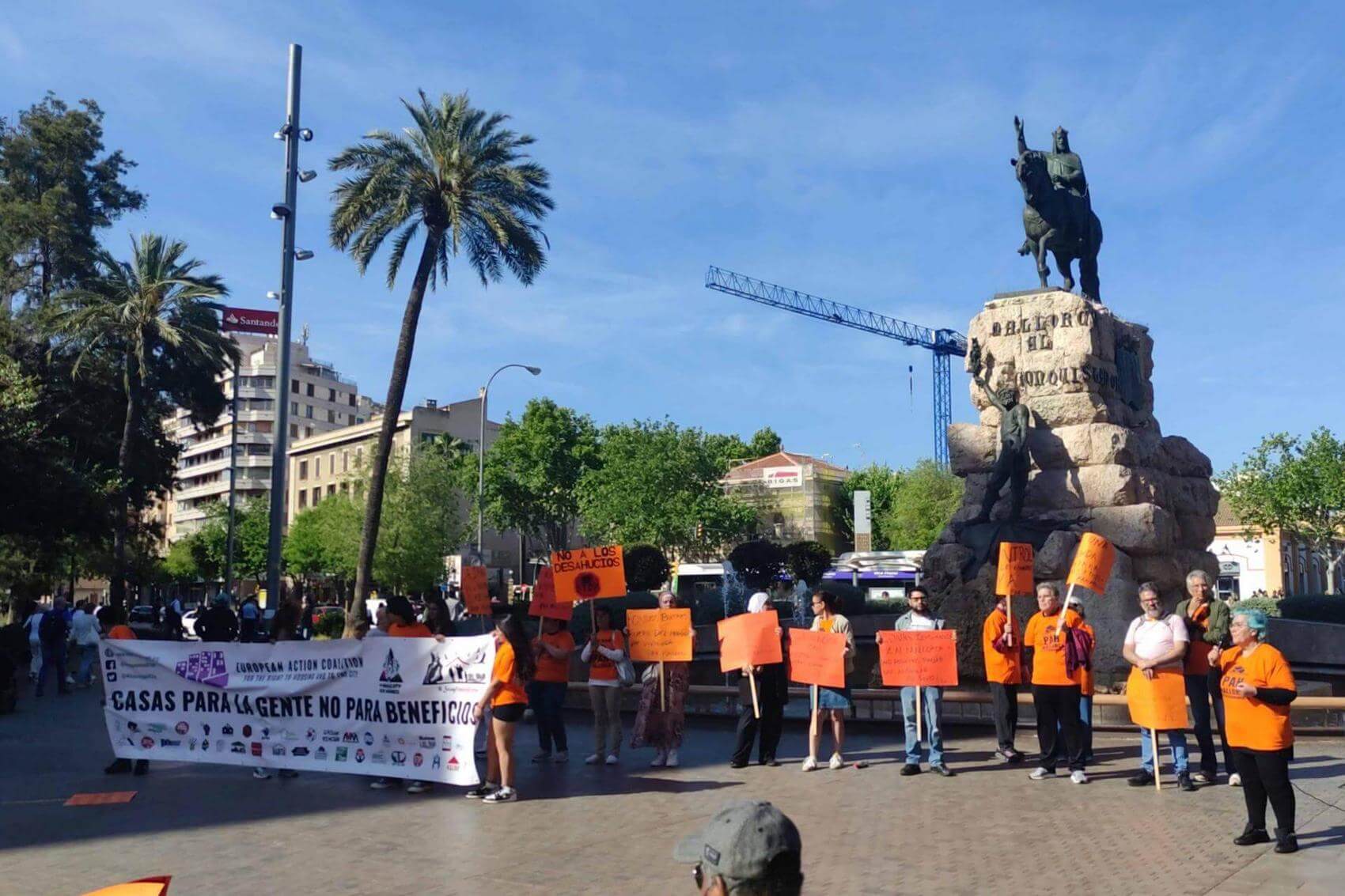 Group of people holding a banner that reads "Homes Not War!" and raising fists.