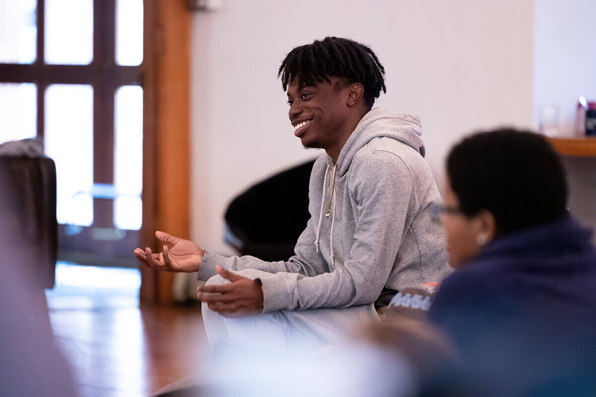 Person seated on a cushion, using a smartphone during a gathering.