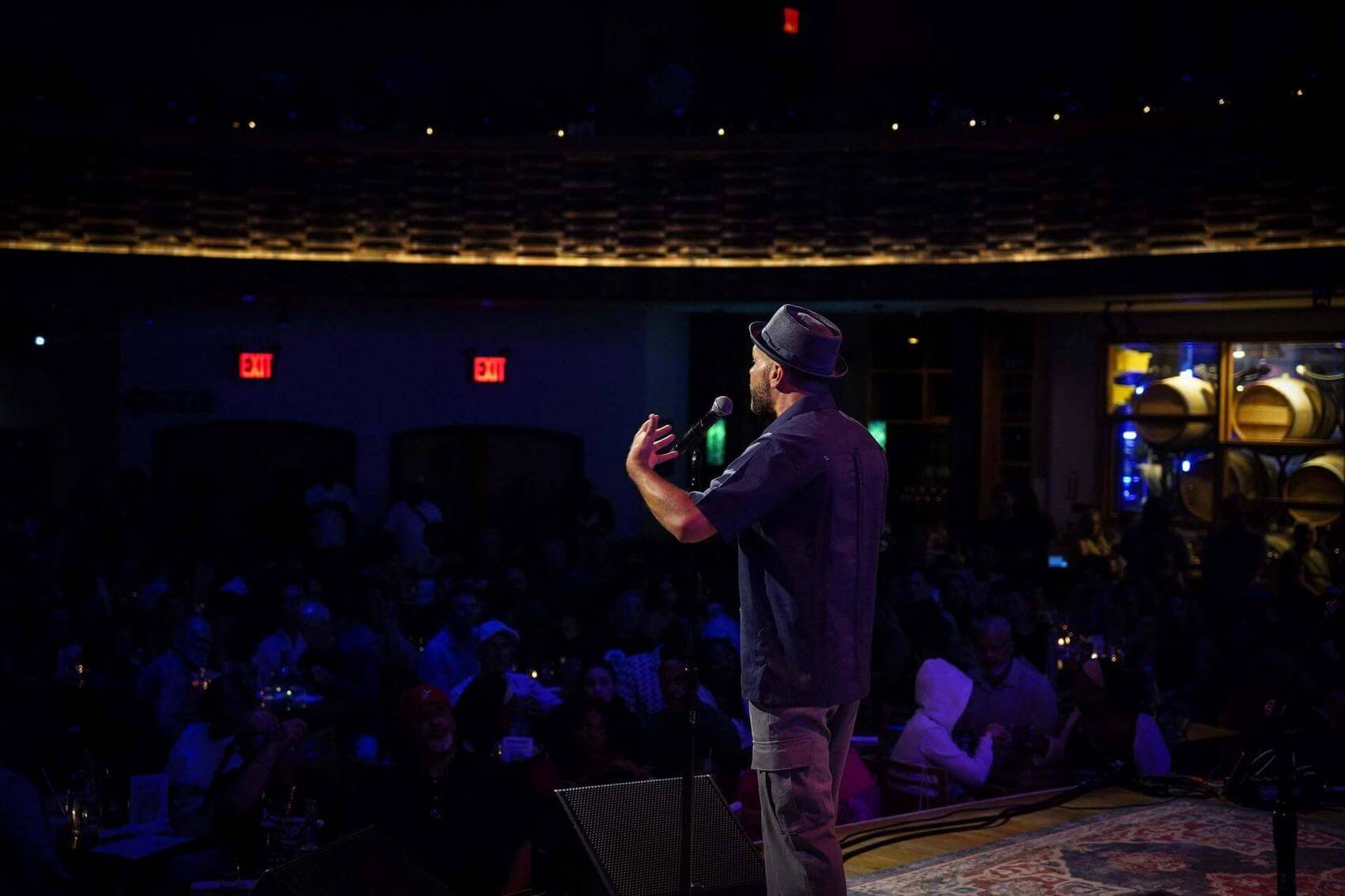 Common holding a book and speaking into a microphone on stage with a band behind.
