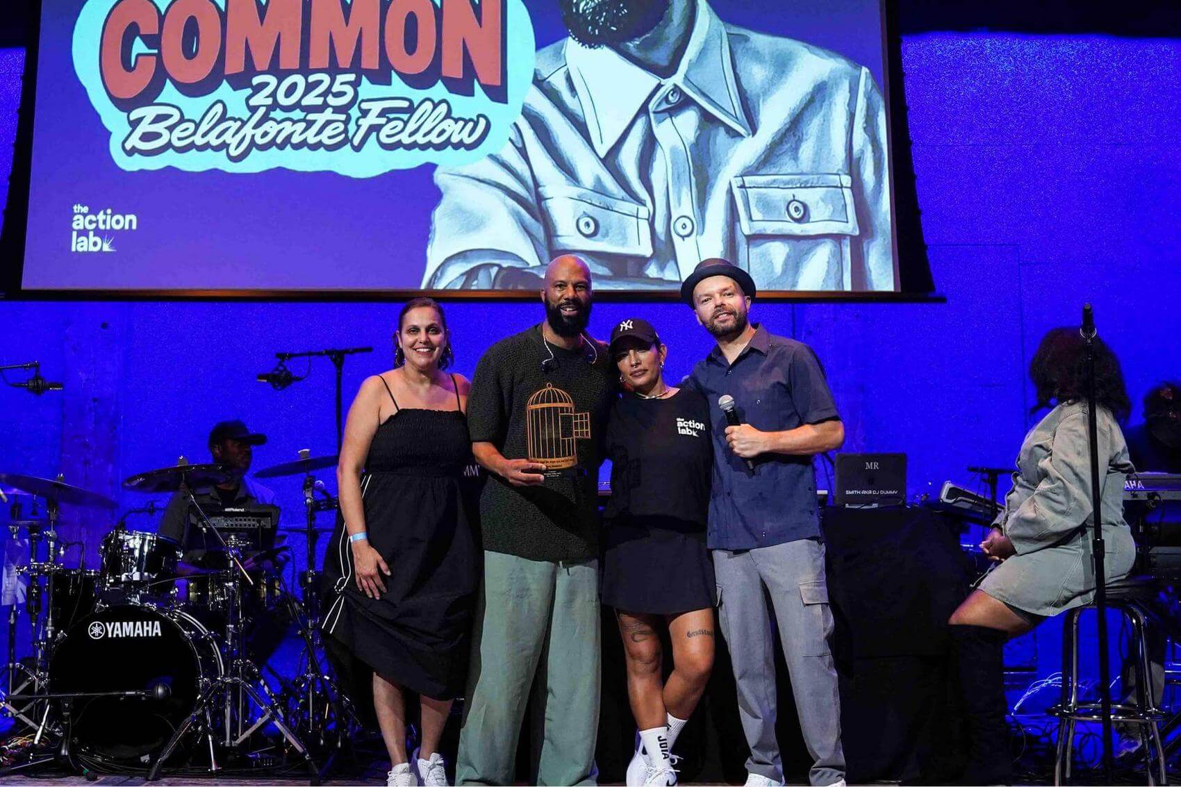 Musician playing an acoustic guitar passionately on stage with a microphone.