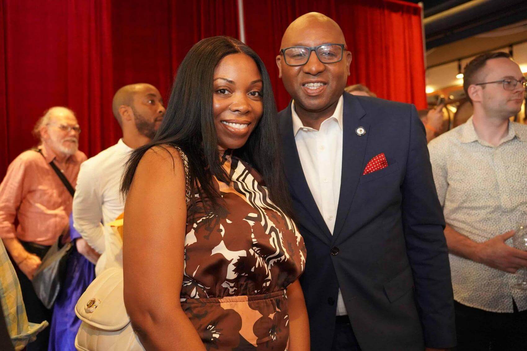 Ana Tijoux singing into a microphone with one arm raised, stage background lit.