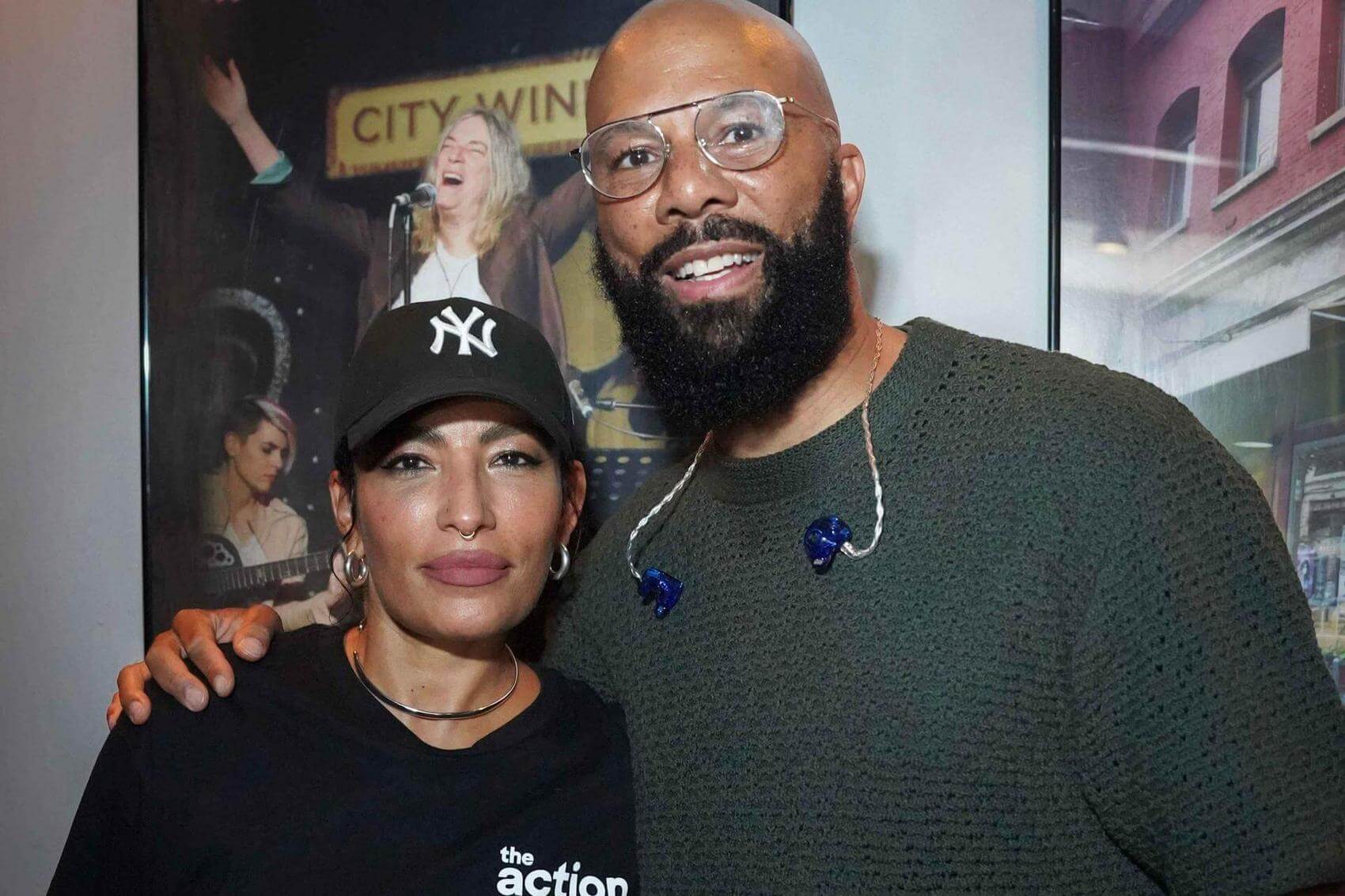 Four people pose together on stage, holding a birdcage with the door open.