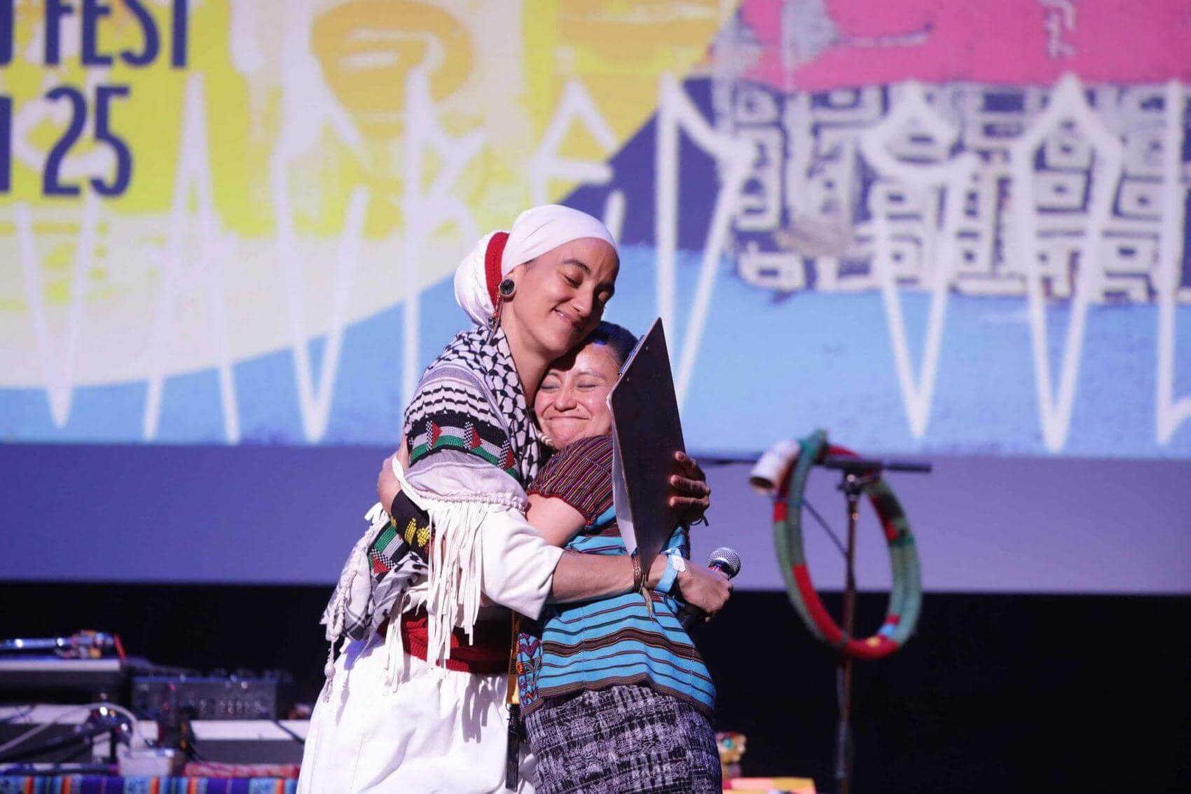 Person singing into a microphone with dramatic lighting in the background.