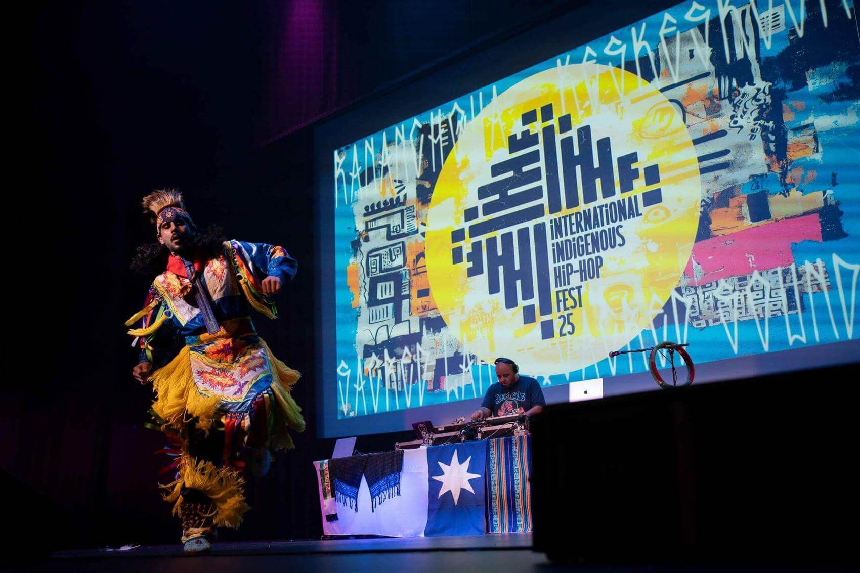 Person holding a microphone, performing on stage with a blurred audience in the background.