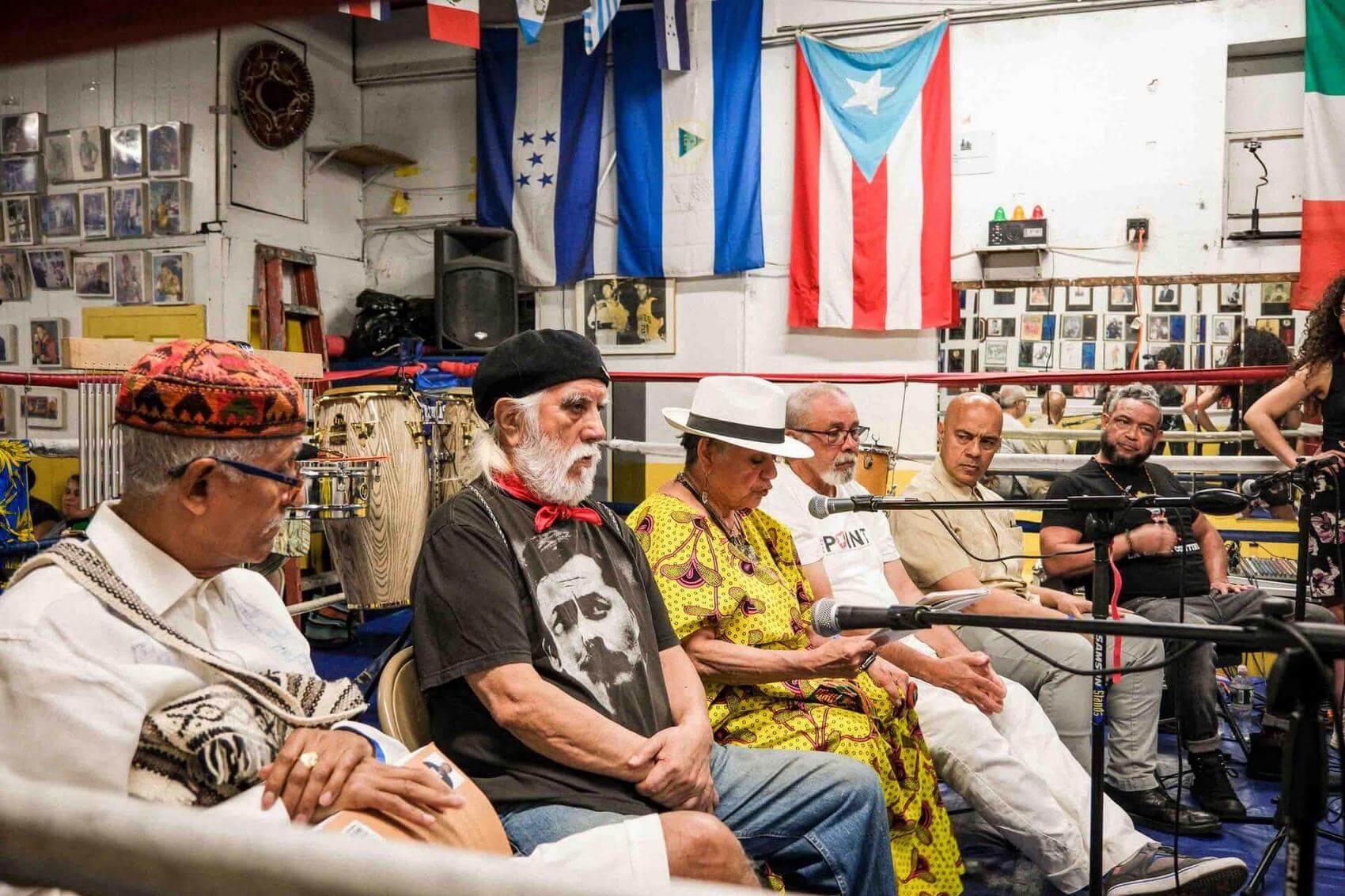 People talking and smiling in a room with a red and black MIR flag on the wall.