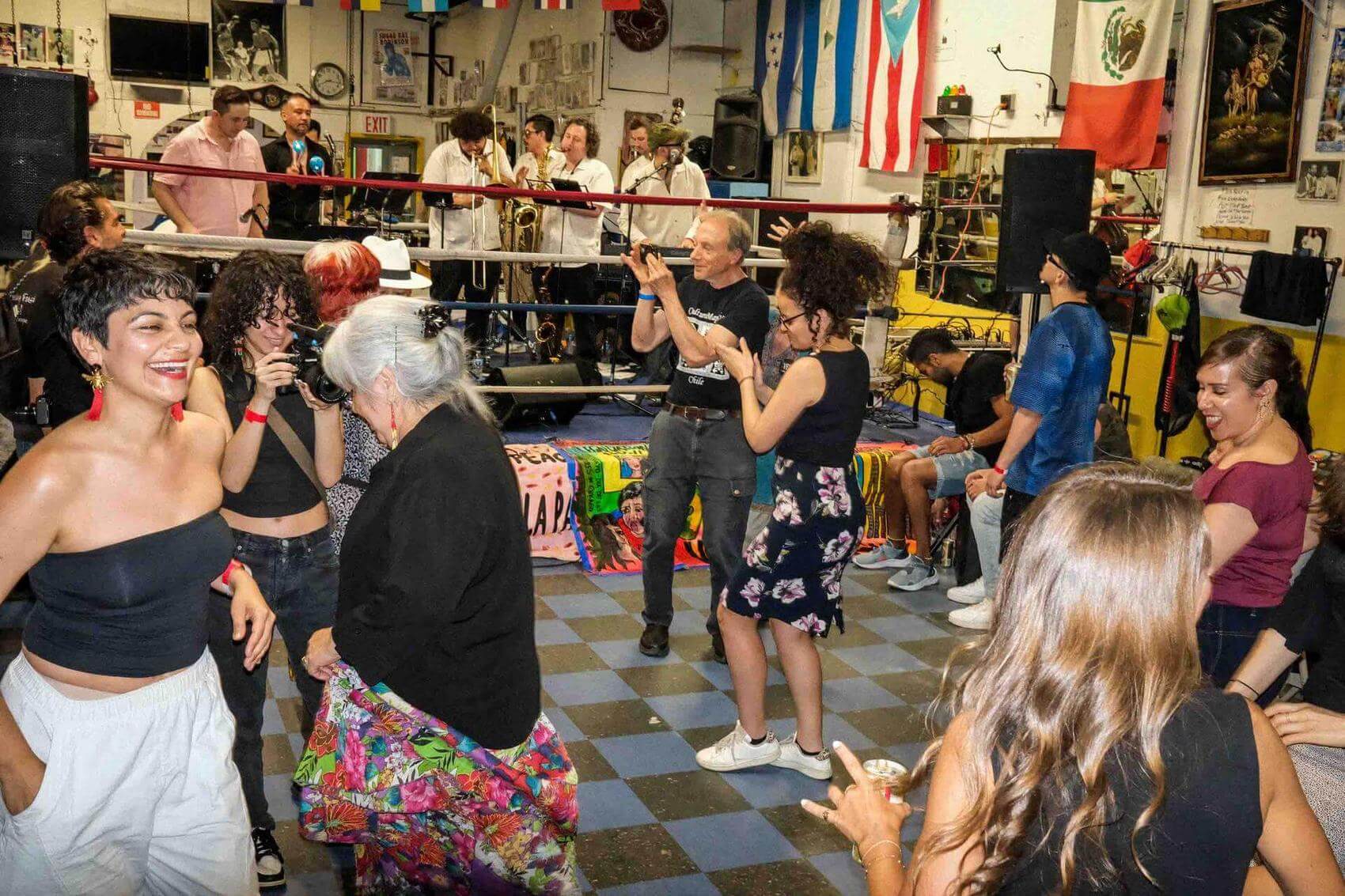 Group of people posing together inside a boxing gym, smiling and standing arm in arm