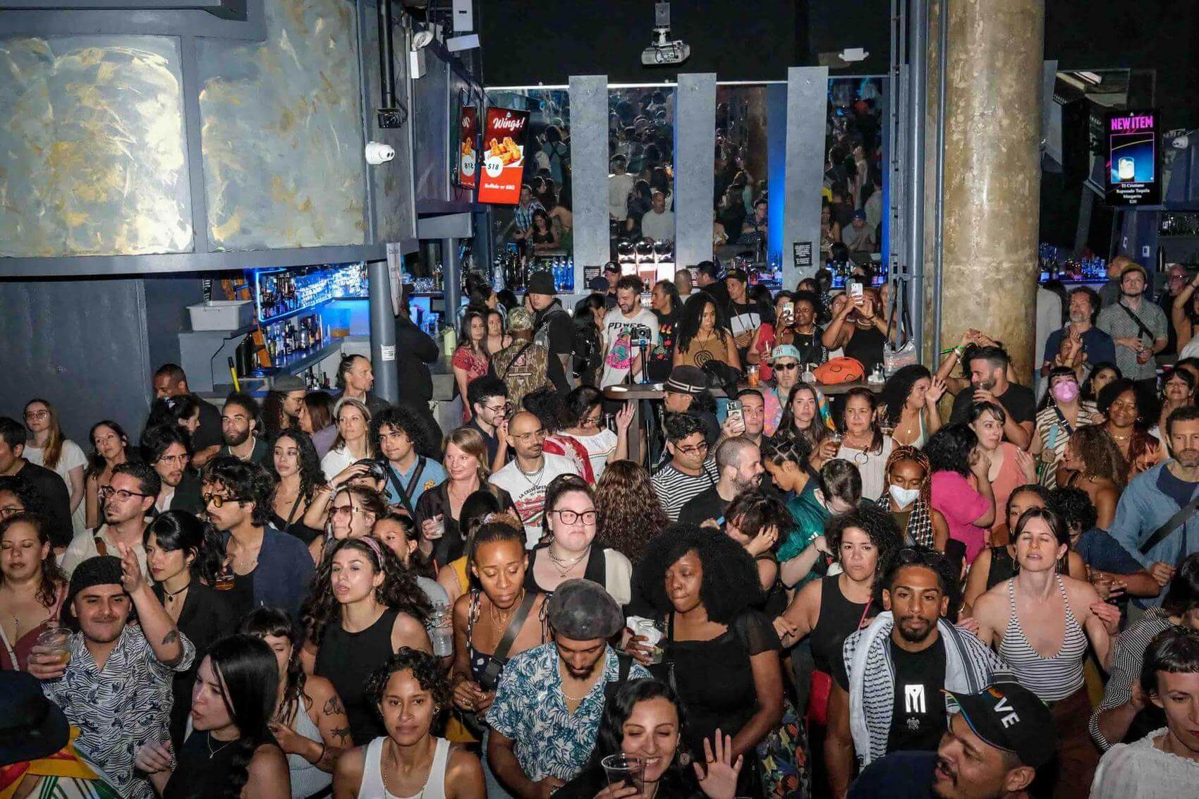 Person wearing a bucket hat and black Southside jersey rapping into a microphone on stage.