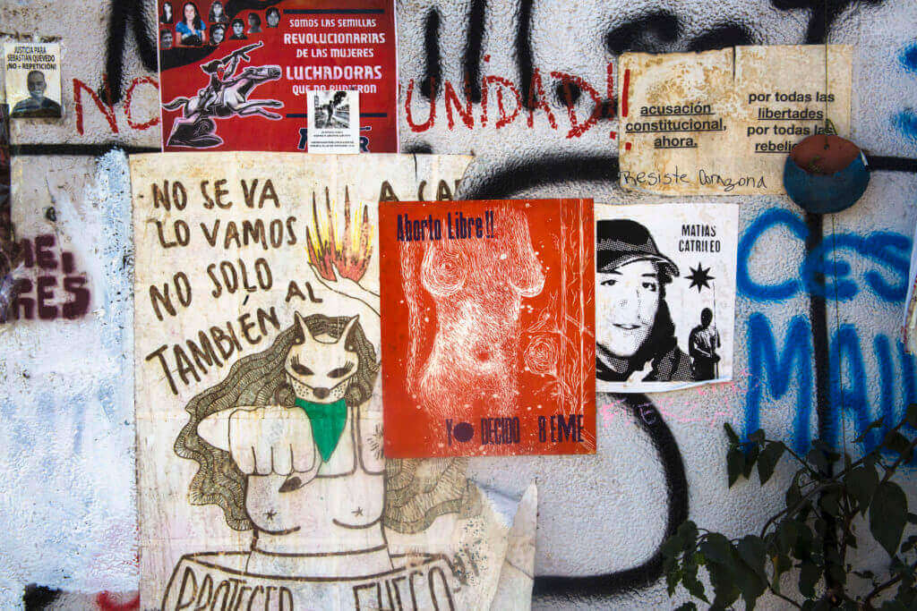 Group of people sitting at tables, raising drinks and smiling in a communal room.