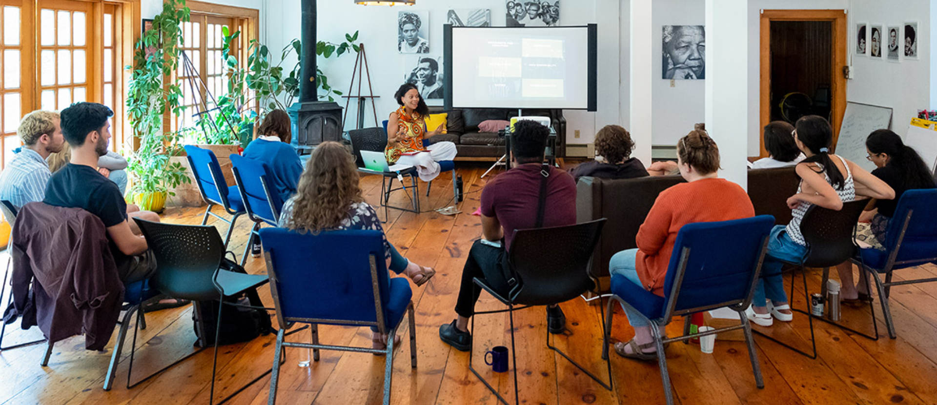 Facilitator leads a small group workshop in a bright room with seated attendees.