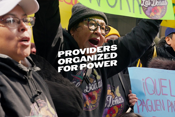 Childcare providers, parents, and advocates rallying outside a government office demanding fair wages and increased funding for childcare in New York.