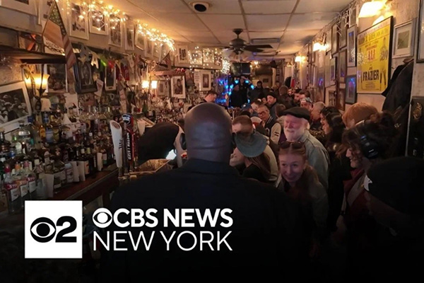 Crowded interior of Jimmy’s Corner in New York City with CBS News New York branding, showing community support for the bar.