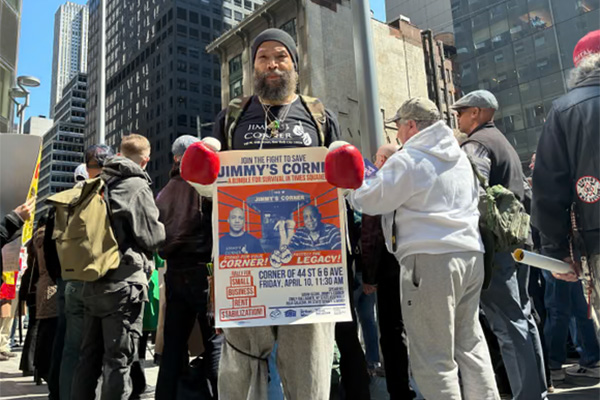 Supporter holding a “Save Jimmy’s Corner” sign with boxing gloves during a rally in Midtown Manhattan advocating for small business protections.