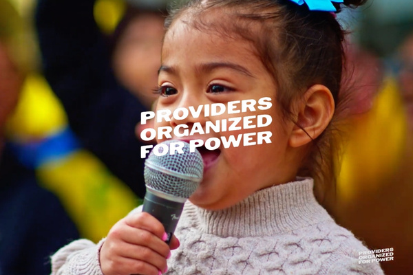 Young child speaking into a microphone at a rally, representing families and childcare providers advocating for fair wages and funding.