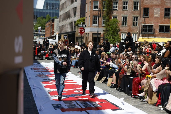 Workers, artists, and organizers participate in the “Ball Without Billionaires” protest fashion show in New York City, carrying a “Labor Is Art” banner during demonstrations opposing billionaire influence and labor exploitation around the Met Gala.