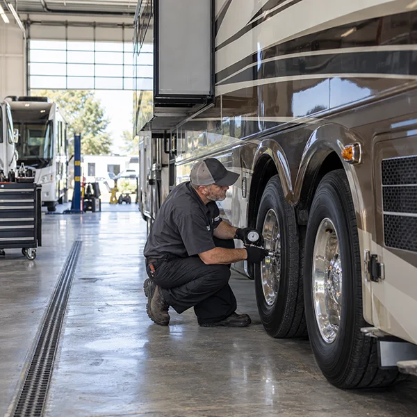 Technician checking the tires of a large motorhome in a service bay