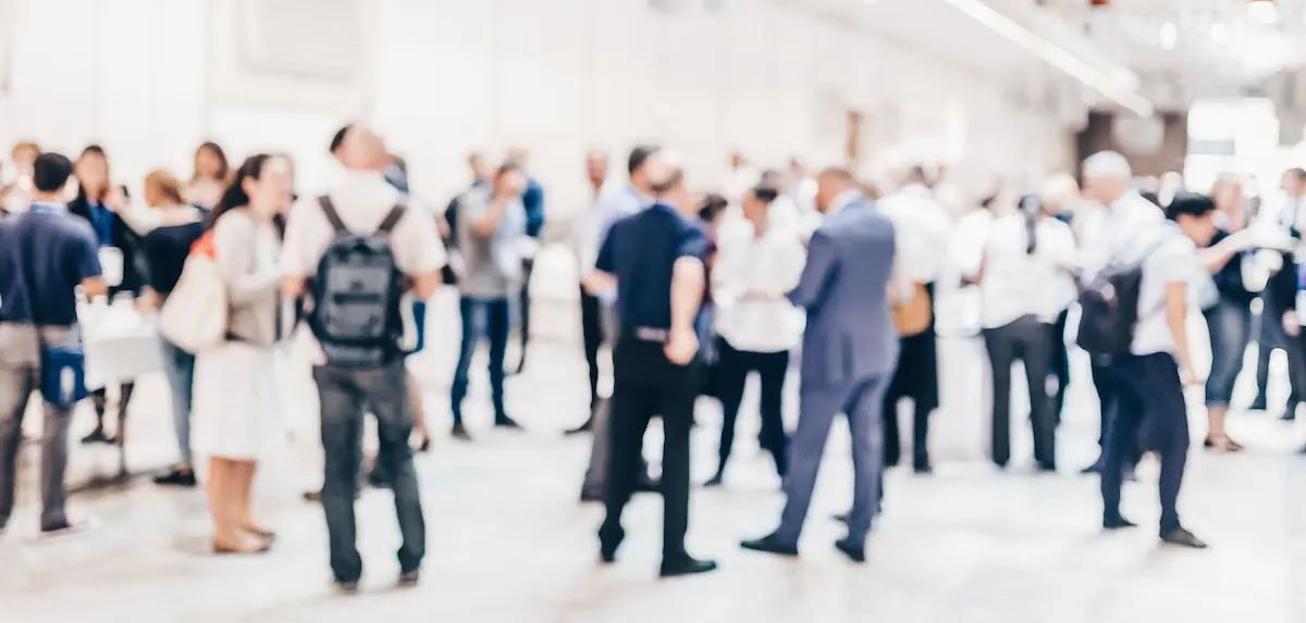 Blurred photo of people standing around at a professional work conference