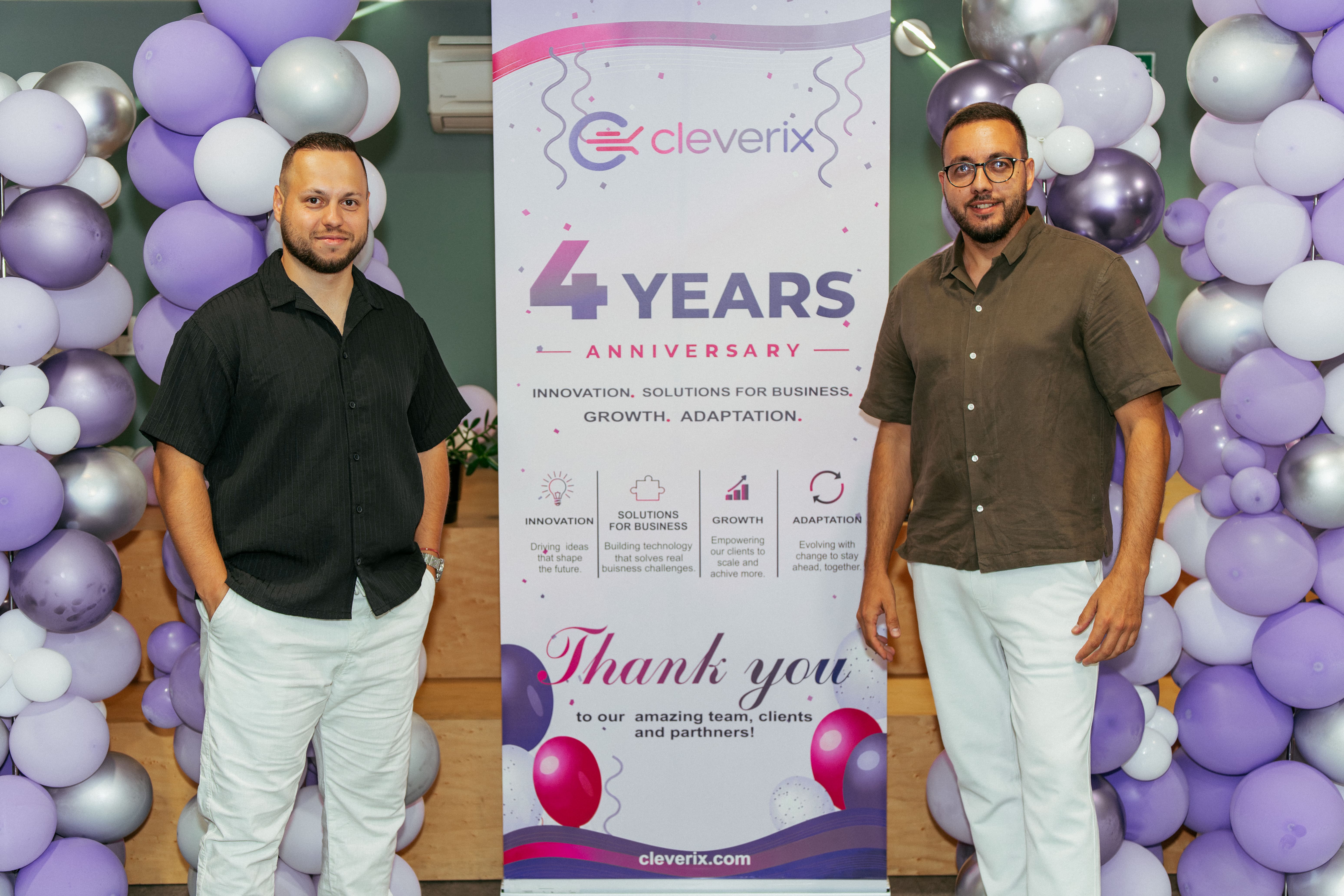 Cleverix founders in front of the four-year anniversary banner