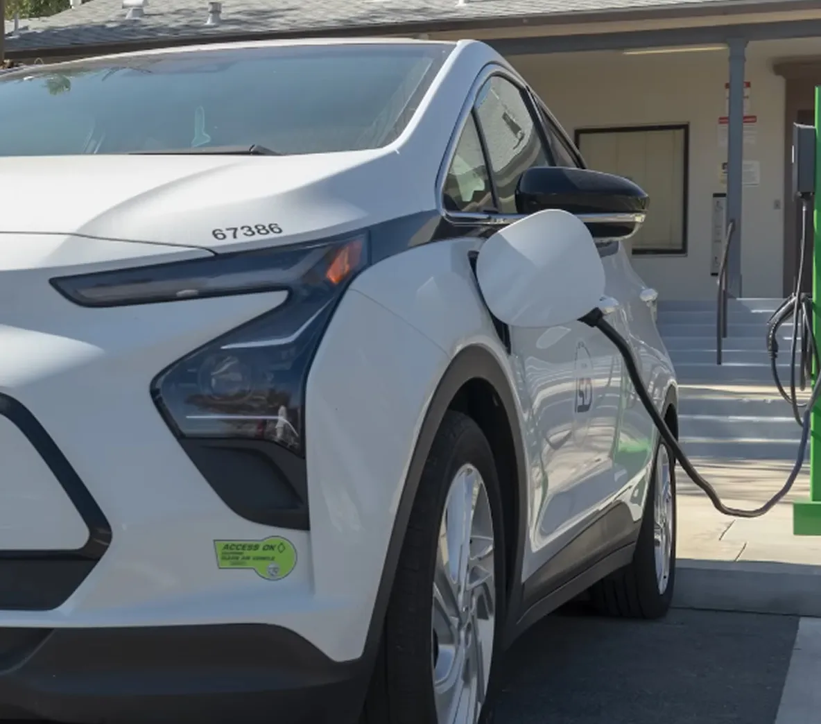 Close-up of an electric car charging with a cable plugged into the port near the rear wheel.