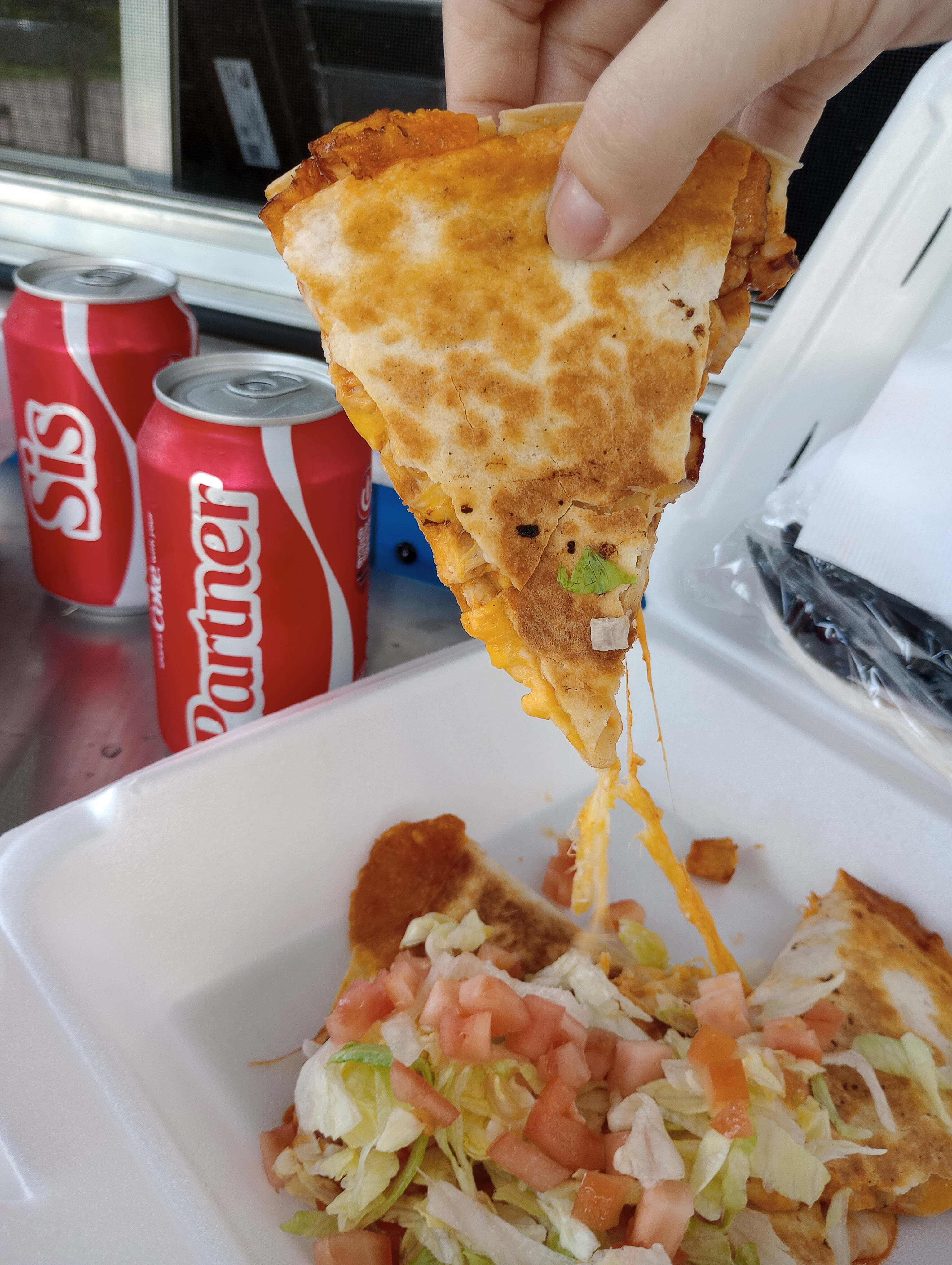 A Buffalo Ranch Chicken Quesadilla dripping with melted cheese and topped with chopped tomatoes and fresh, shredded iceberg lettuce.
