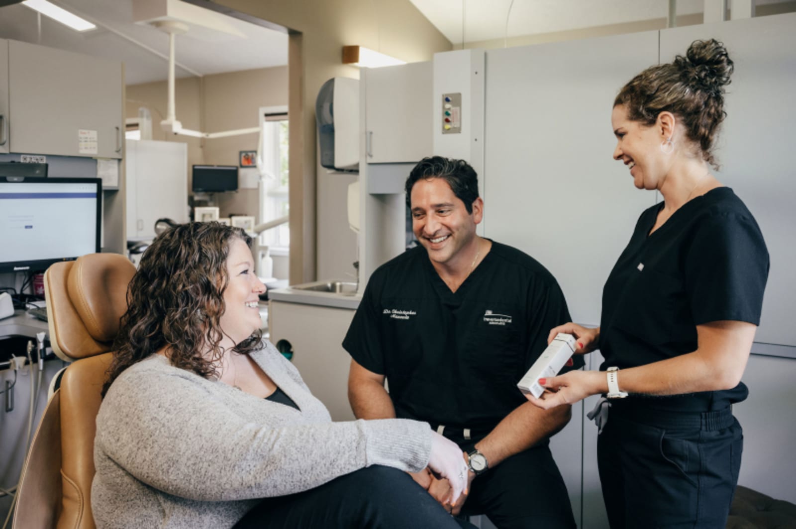 Female dentist in white coat consulting with patient in treatment chair