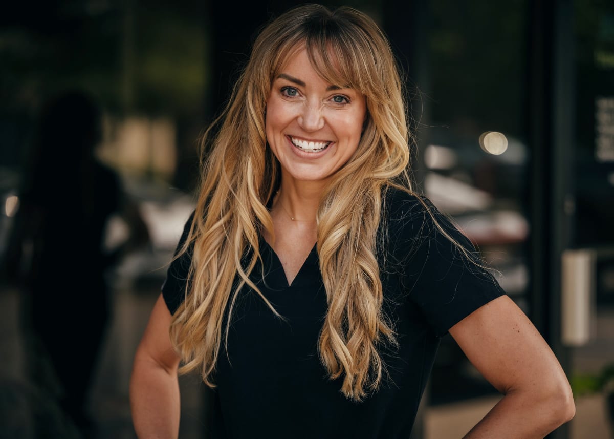Professional female dentist in dark blazer smiling with arms crossed