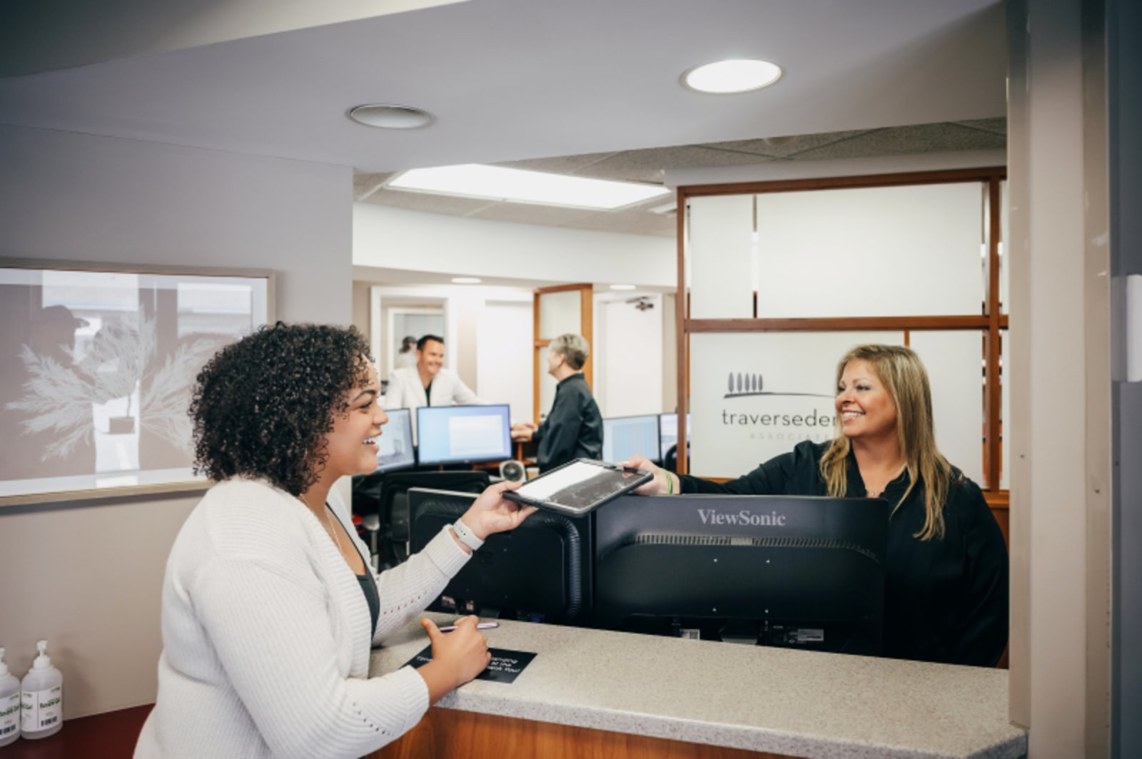 Dental staff member assisting patient at reception desk in office setting