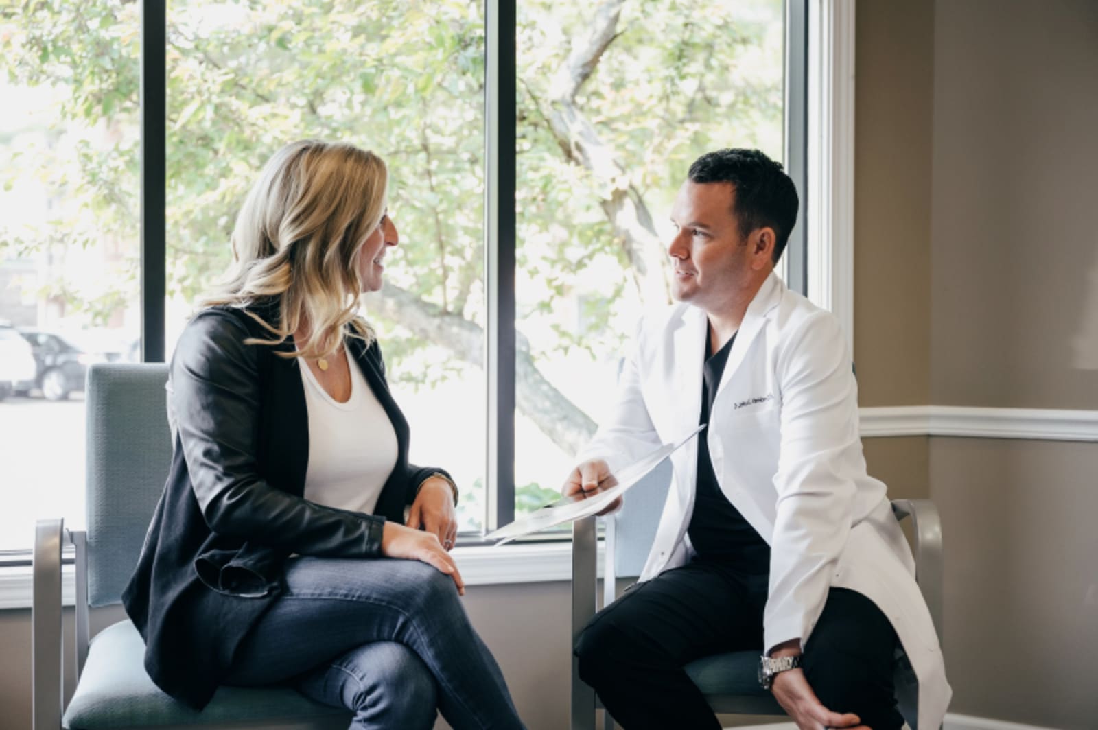 Dentist consulting with patient while reviewing treatment plan by window