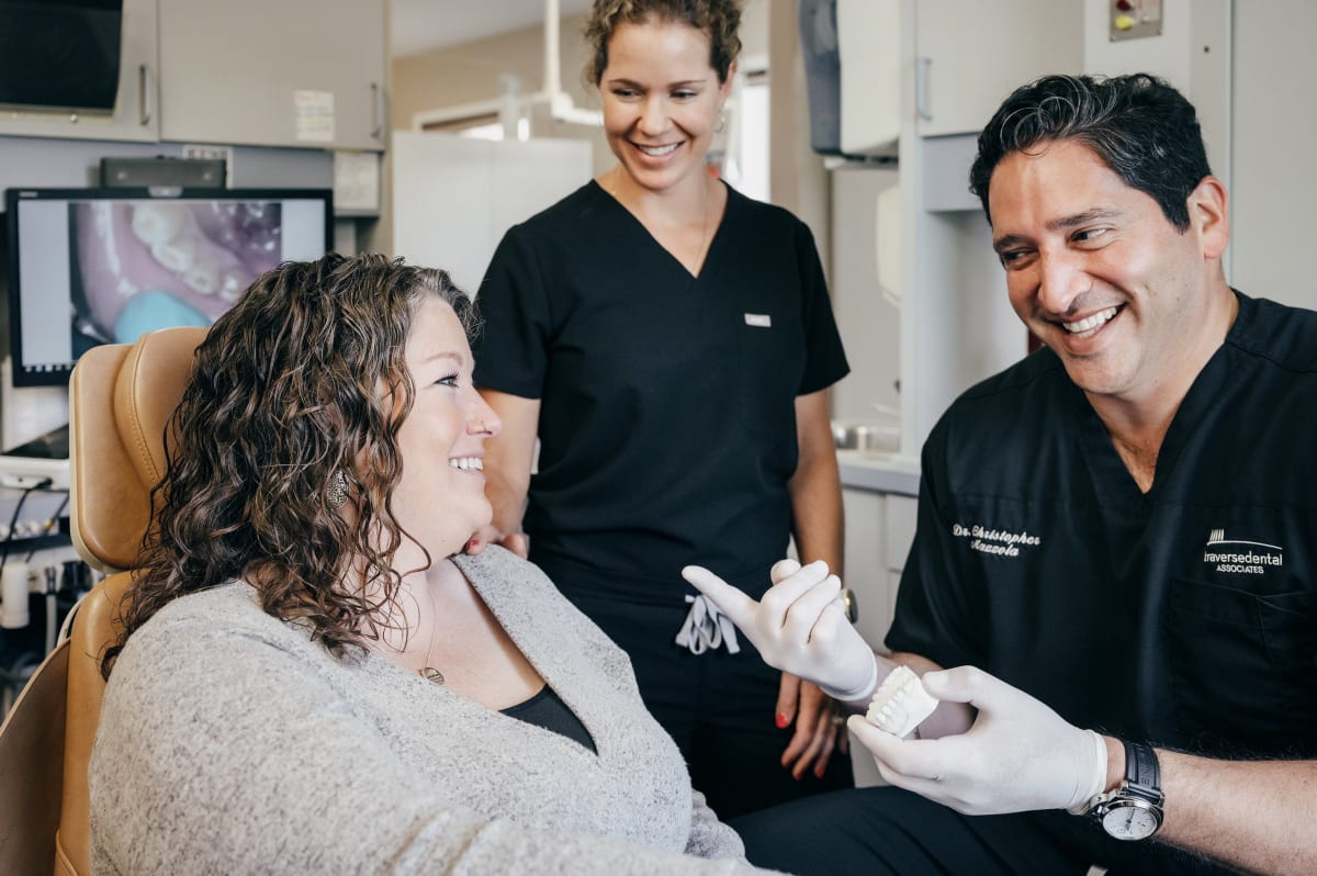 Dental team member examining patient's teeth during clinical consultation