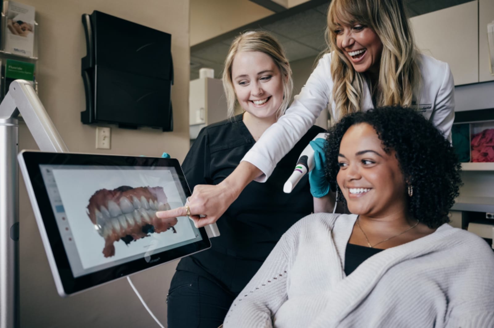 Dental professional showing treatment plan on screen to two female patients in office