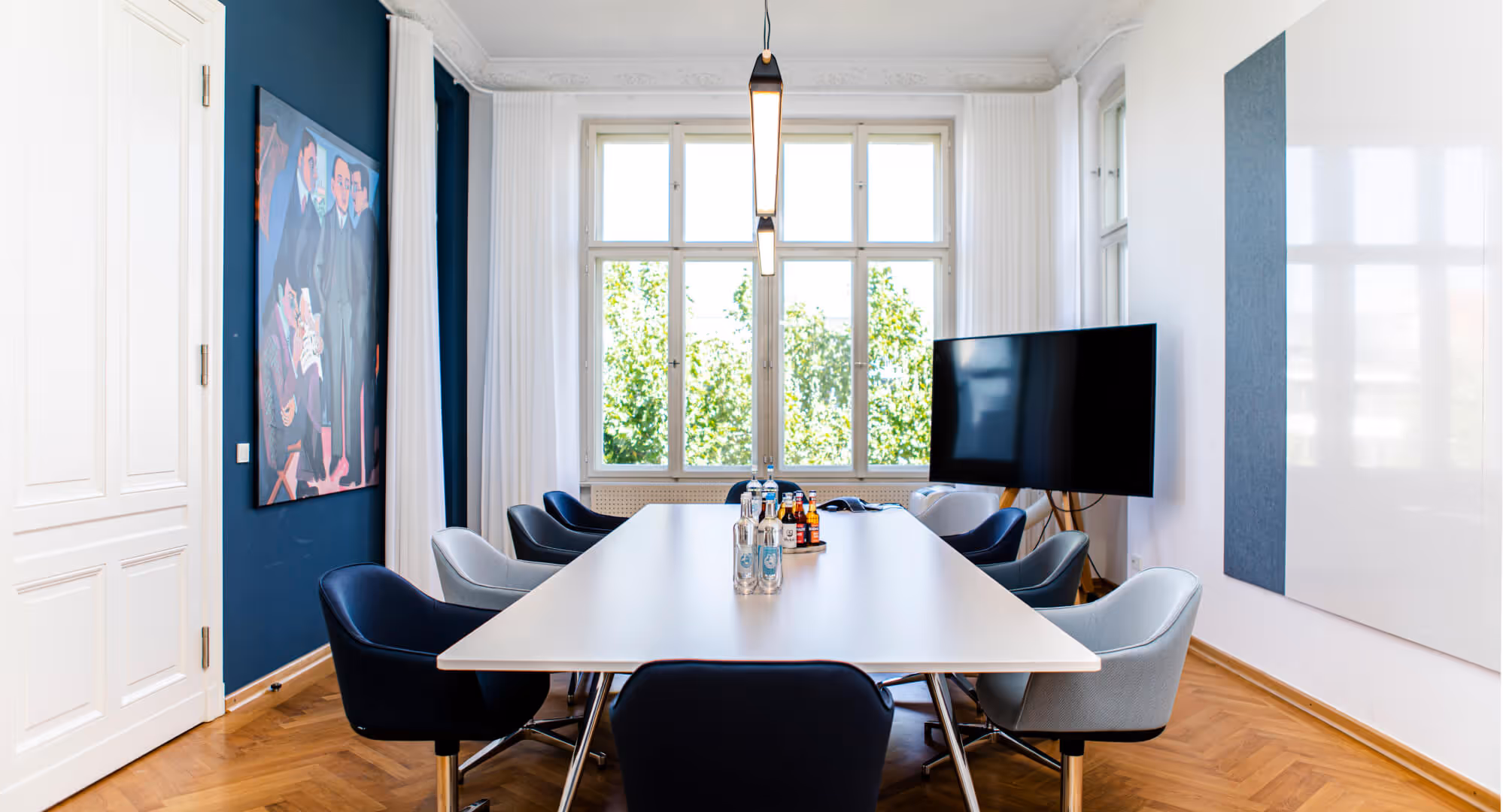 Moderner Konferenzraum mit weißem Tisch, blauen Stühlen und Kunstwerk