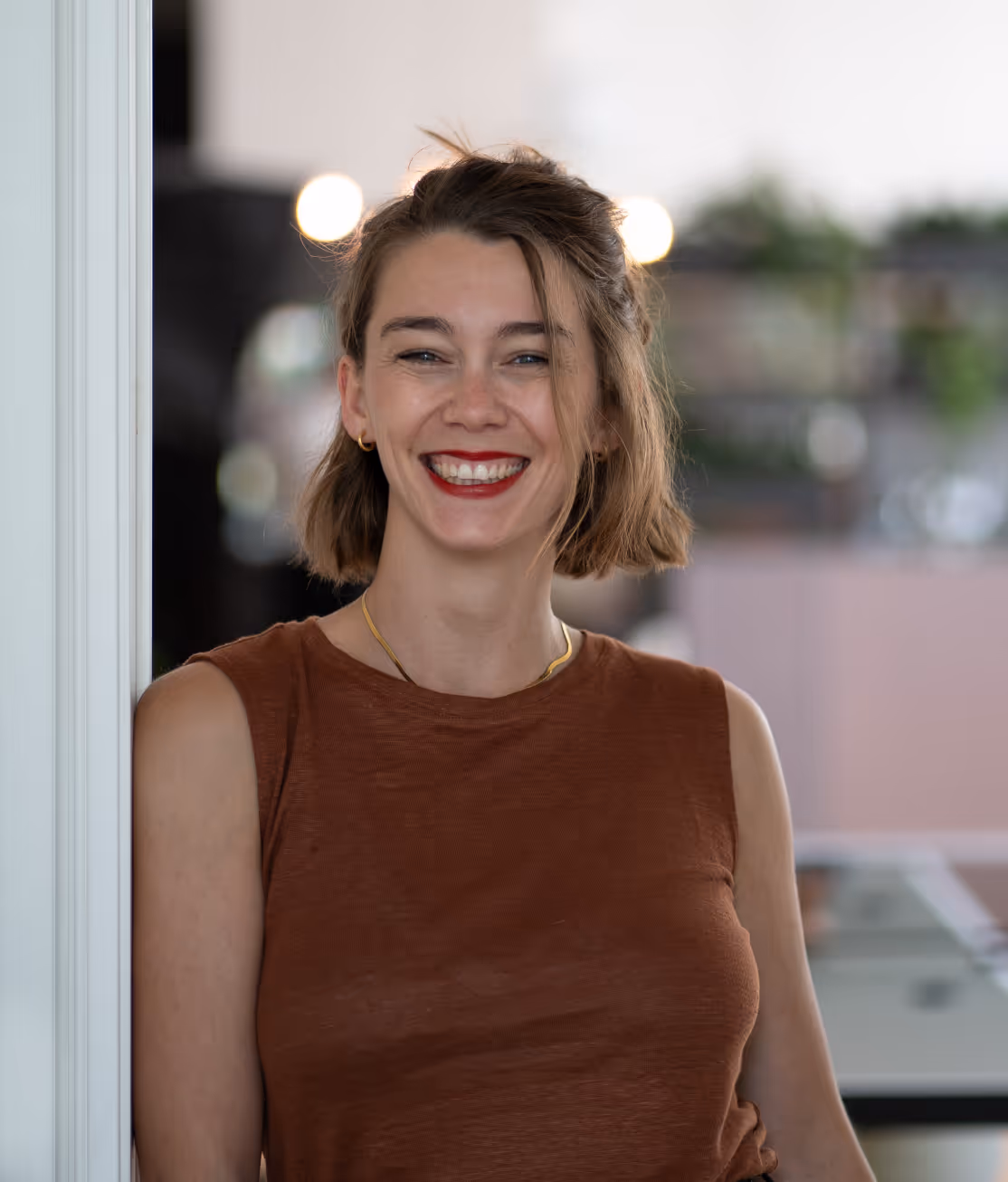 Ramona Kors braunem Top, die an einem Fenster steht