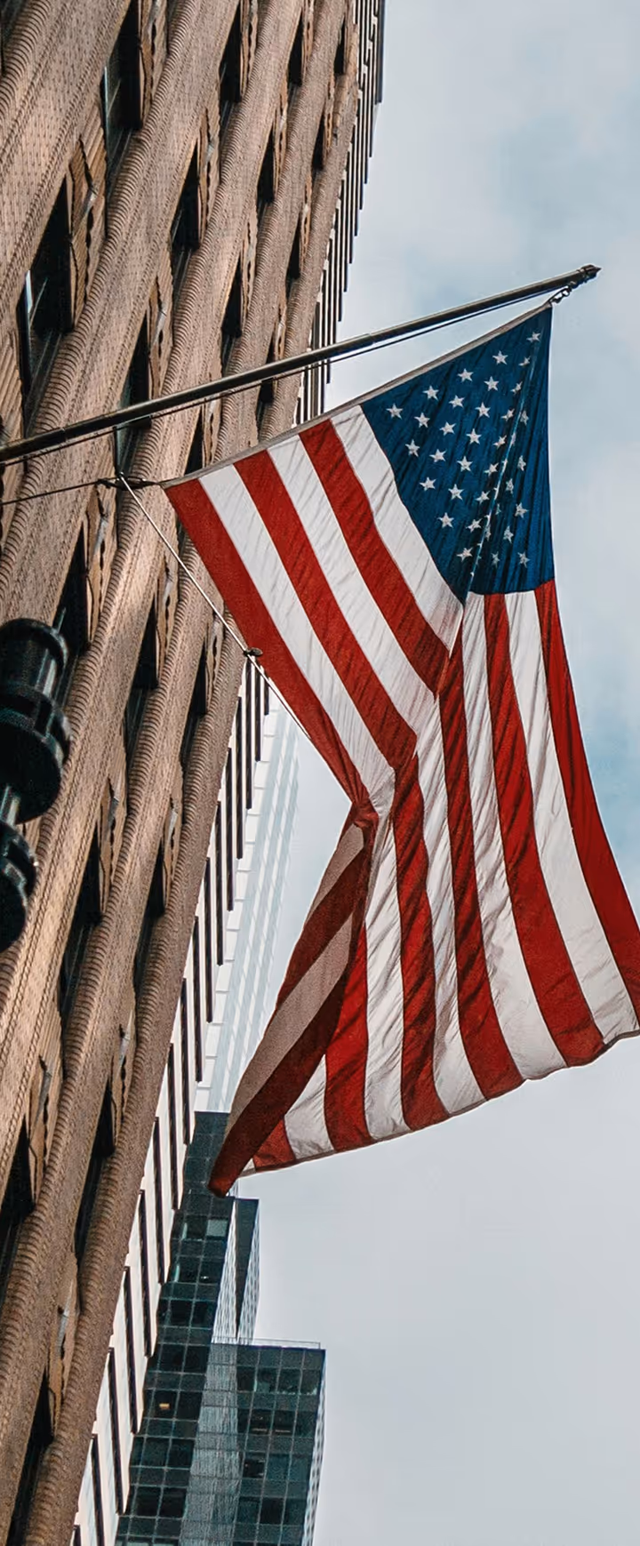 Amerikanische Flagge weht vor Backsteingebäude in urbaner Stadtlandschaft