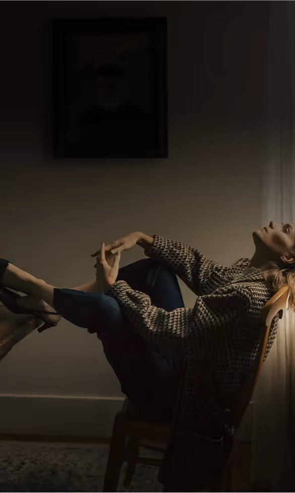 Person in gemusterter Jacke lehnt sich zurück, dramatisch beleuchtet