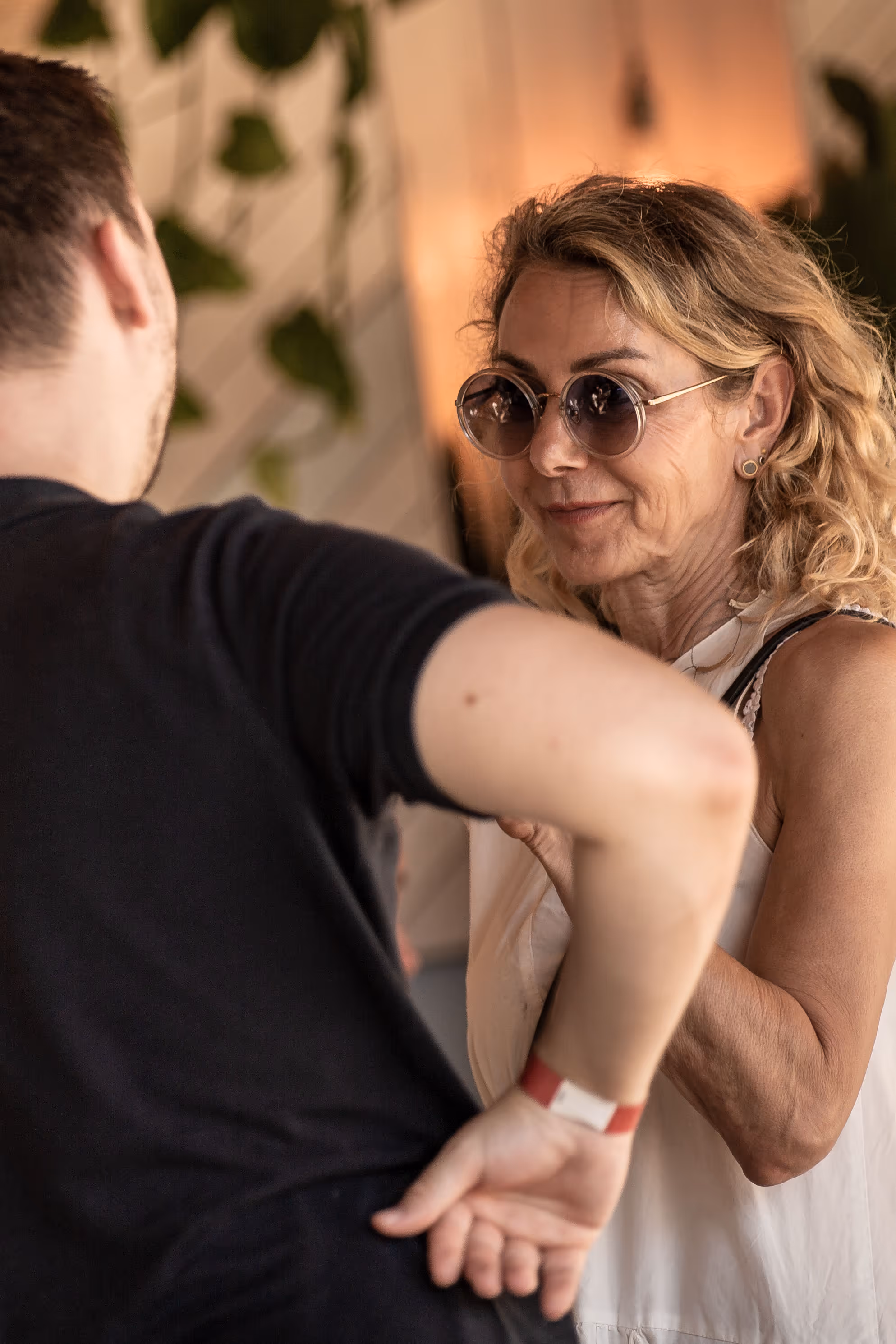Zwei Personen tanzen eng beieinander, Frau mit Sonnenbrille lächelt