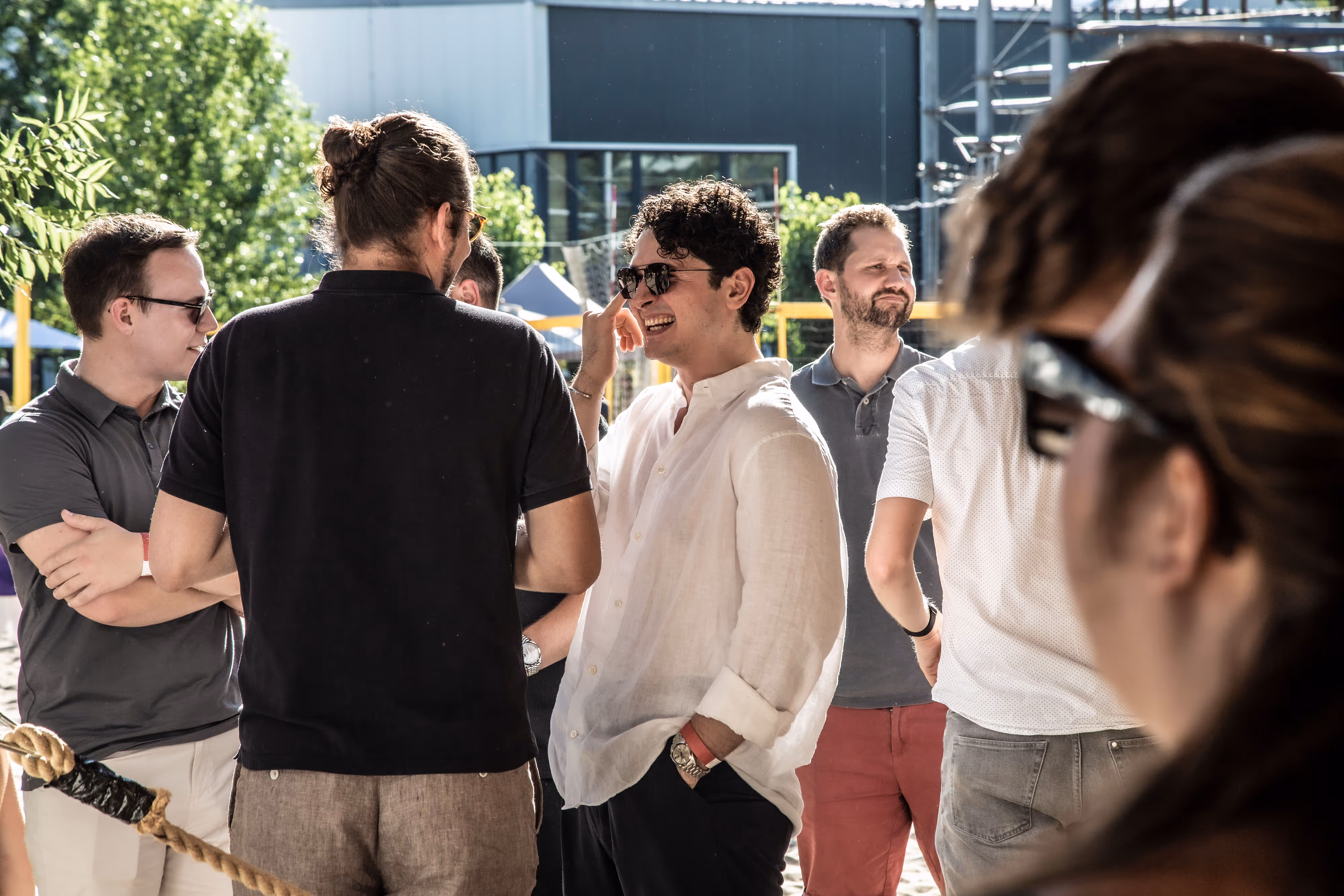 Gruppe von Kollegen unterhält sich lachend im Freien bei sonnigem Wetter