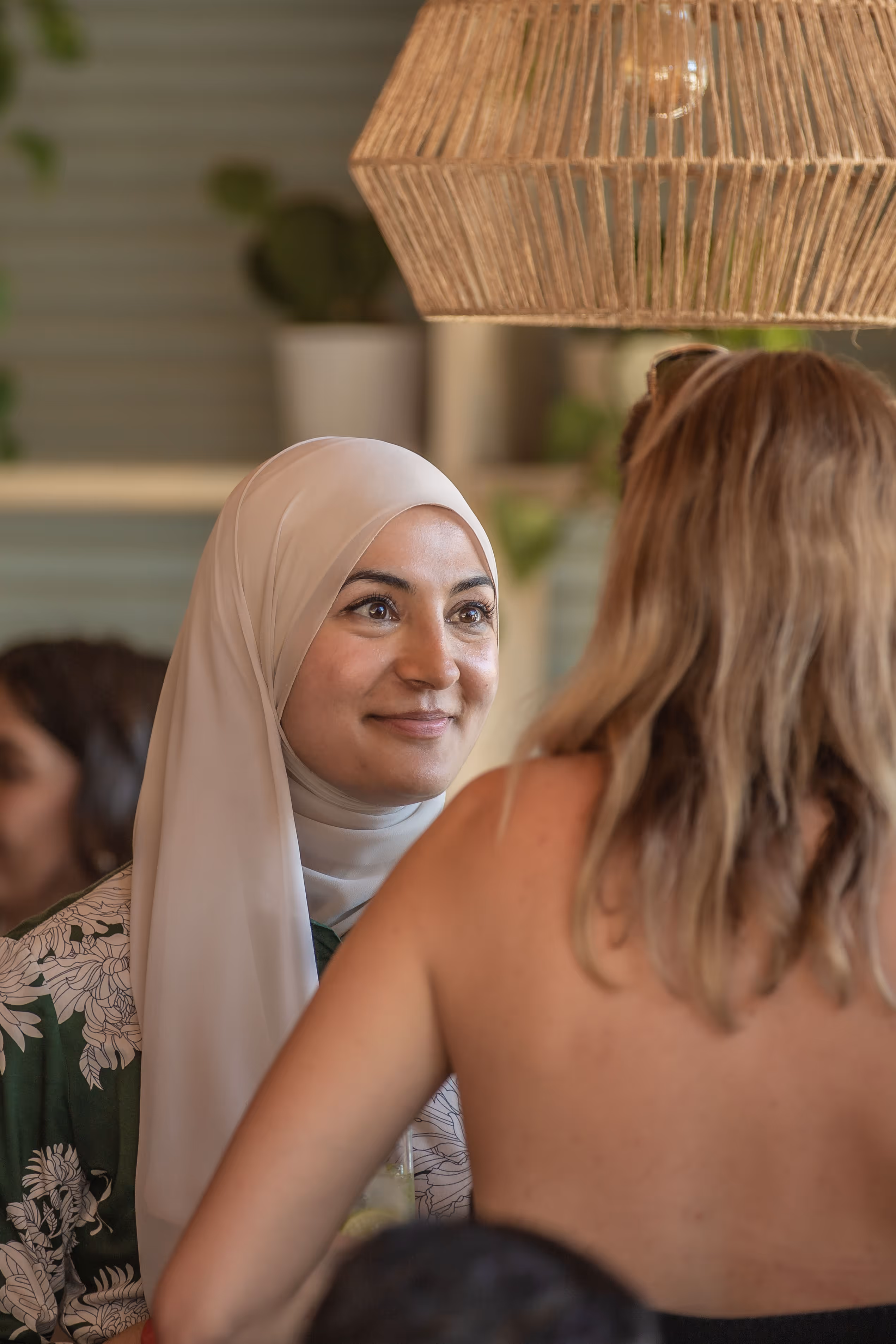 Lächelnde Frau mit Hijab im Gespräch in gemütlichem Innenraum