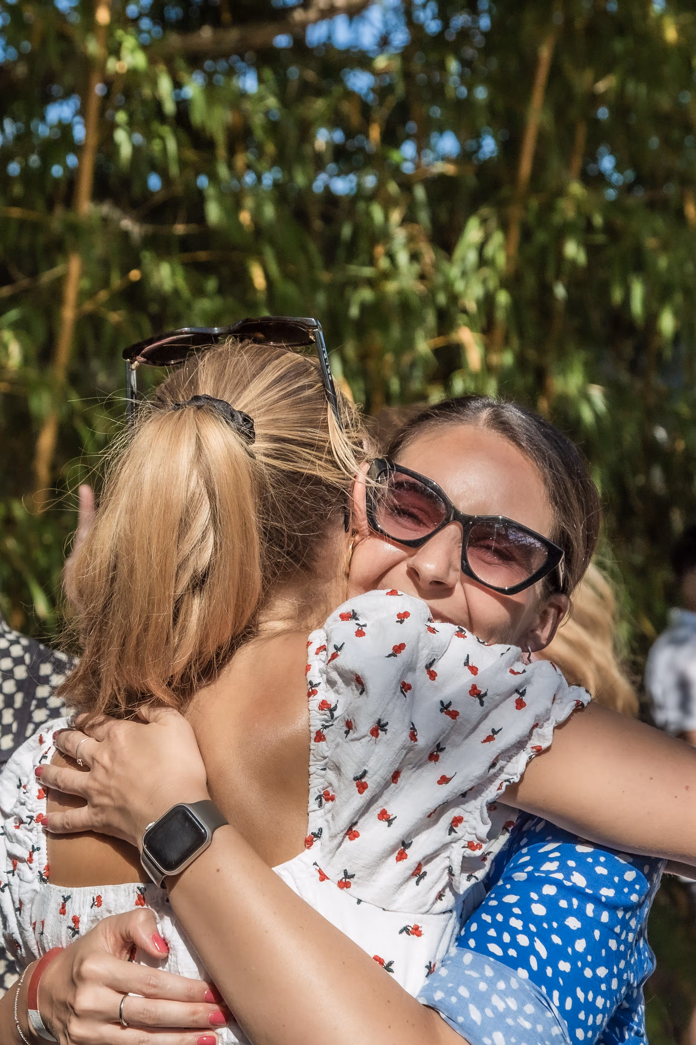 Zwei Freundinnen umarmen sich herzlich im Freien mit Sonnenbrille