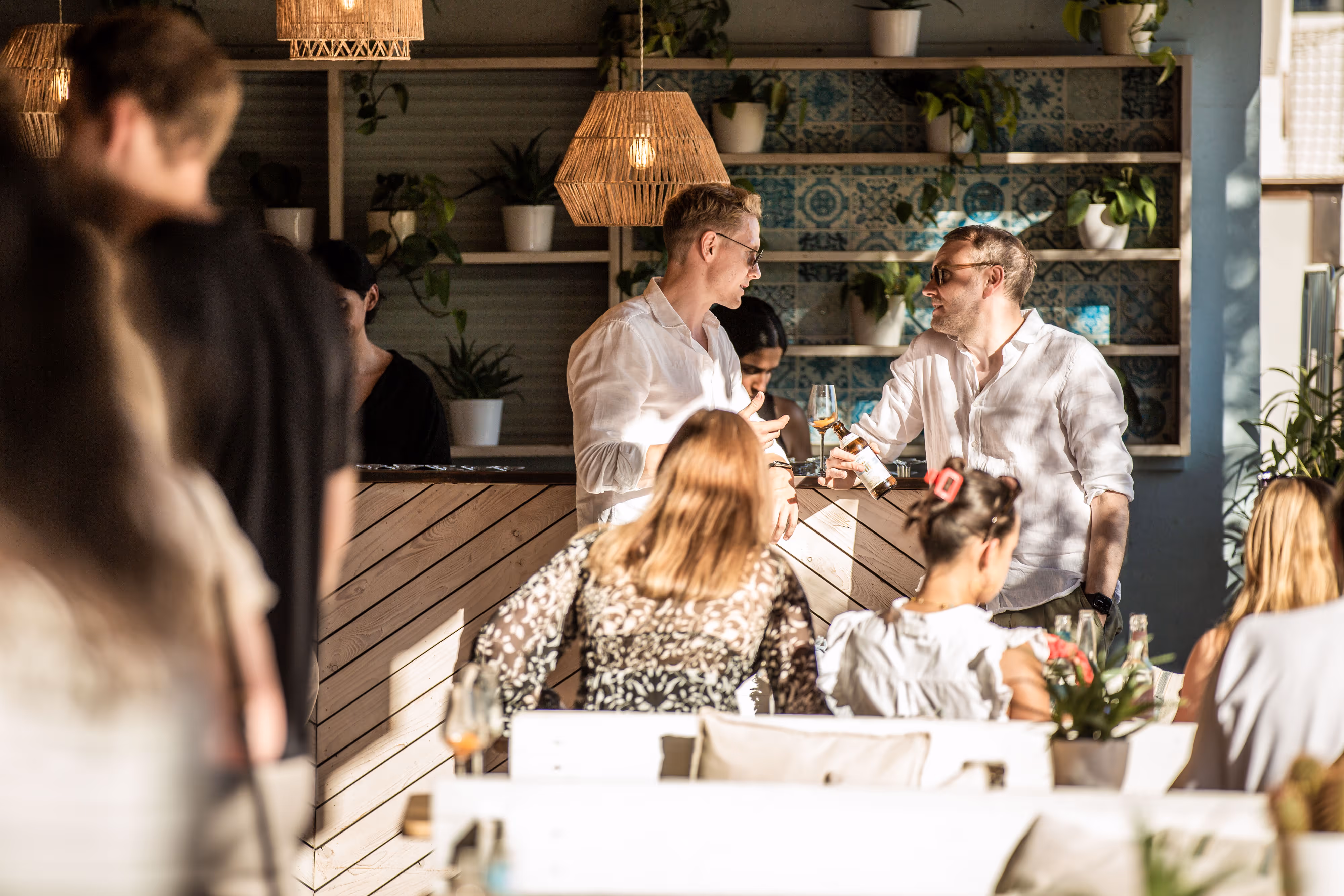 Zwei Männer diskutieren in einem modernen, pflanzenvollen Café