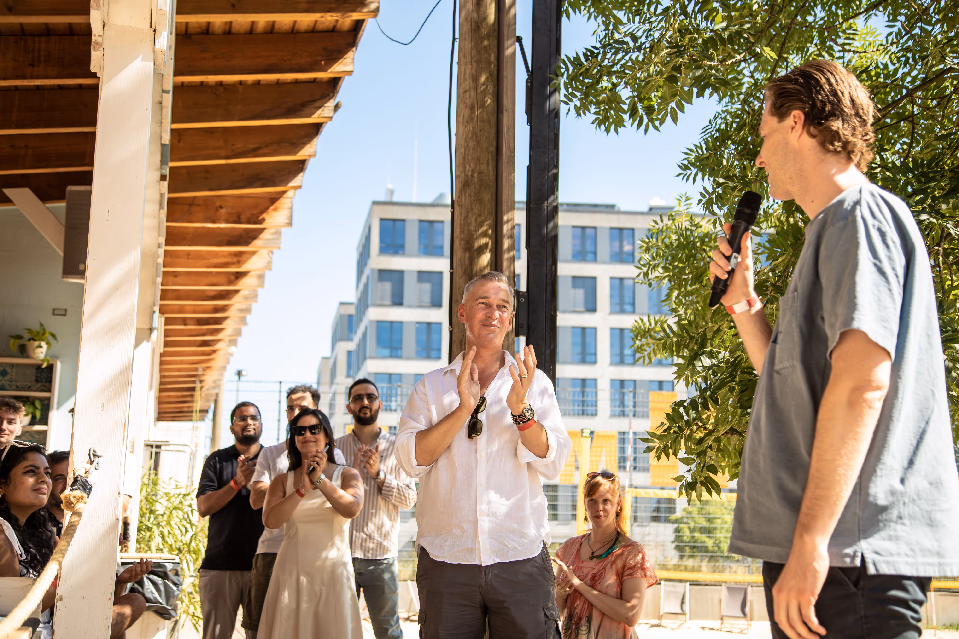 Gruppe applaudiert während einer Präsentation auf einer sonnigen Terrasse