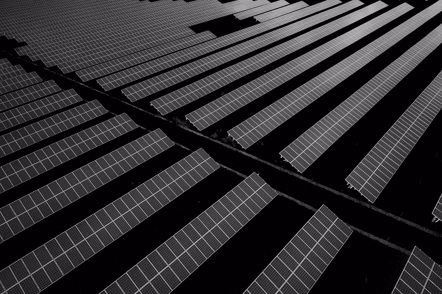 Schwarzweißaufnahme eines großen Solarparks mit geometrisch angeordneten Sonnenkollektoren