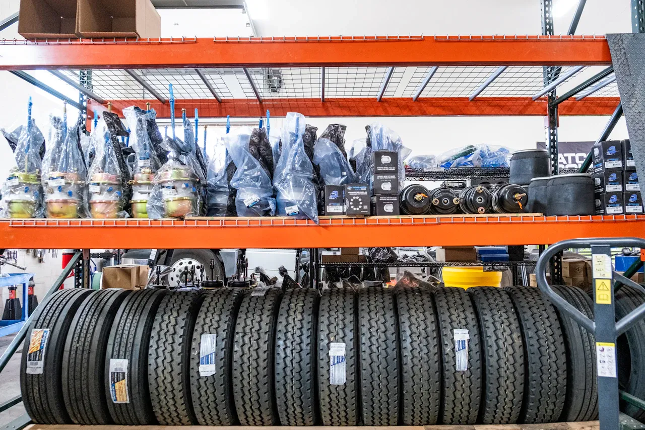 Heavy-duty truck tires and replacement parts stocked on warehouse shelves in a commercial repair facility.
