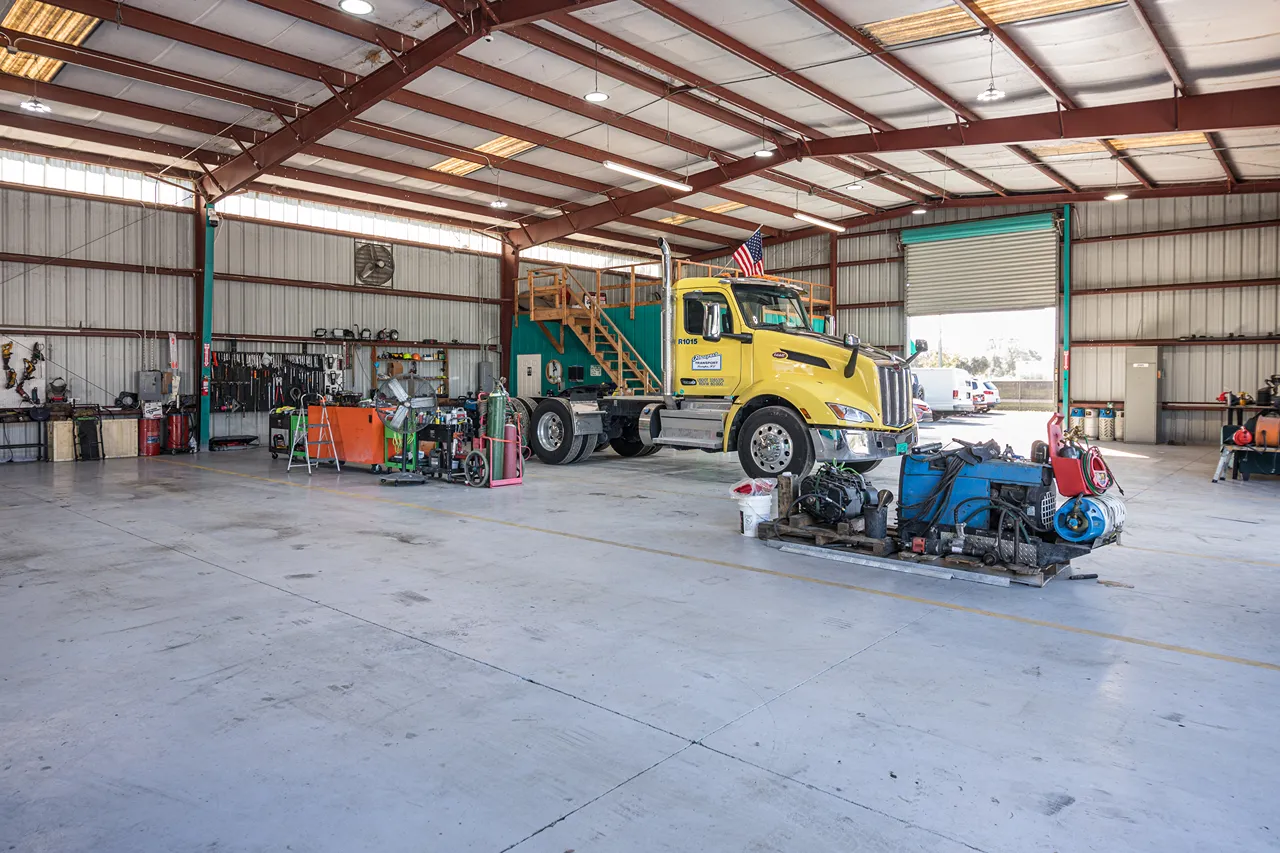 Heavy equipment inspection of a yellow truck in a Florida repair bay before peak storm season ends.
