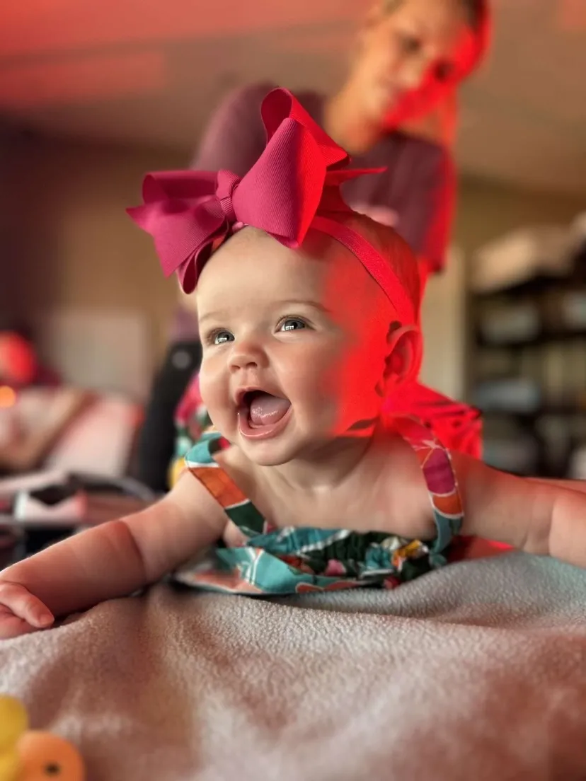A small toddler laughing while receiving laser therapy treatments at NeuroSolution Center of Lake Charles.