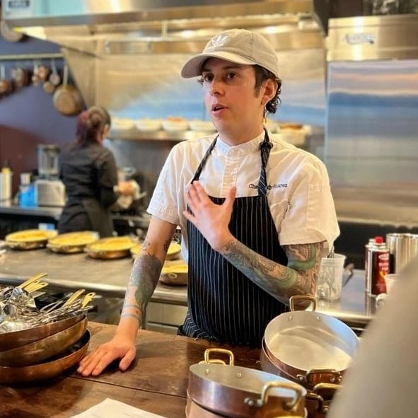 Andy Suarez, a Chicago chef, passionately teaches and connects people through food in a vibrant kitchen setting.